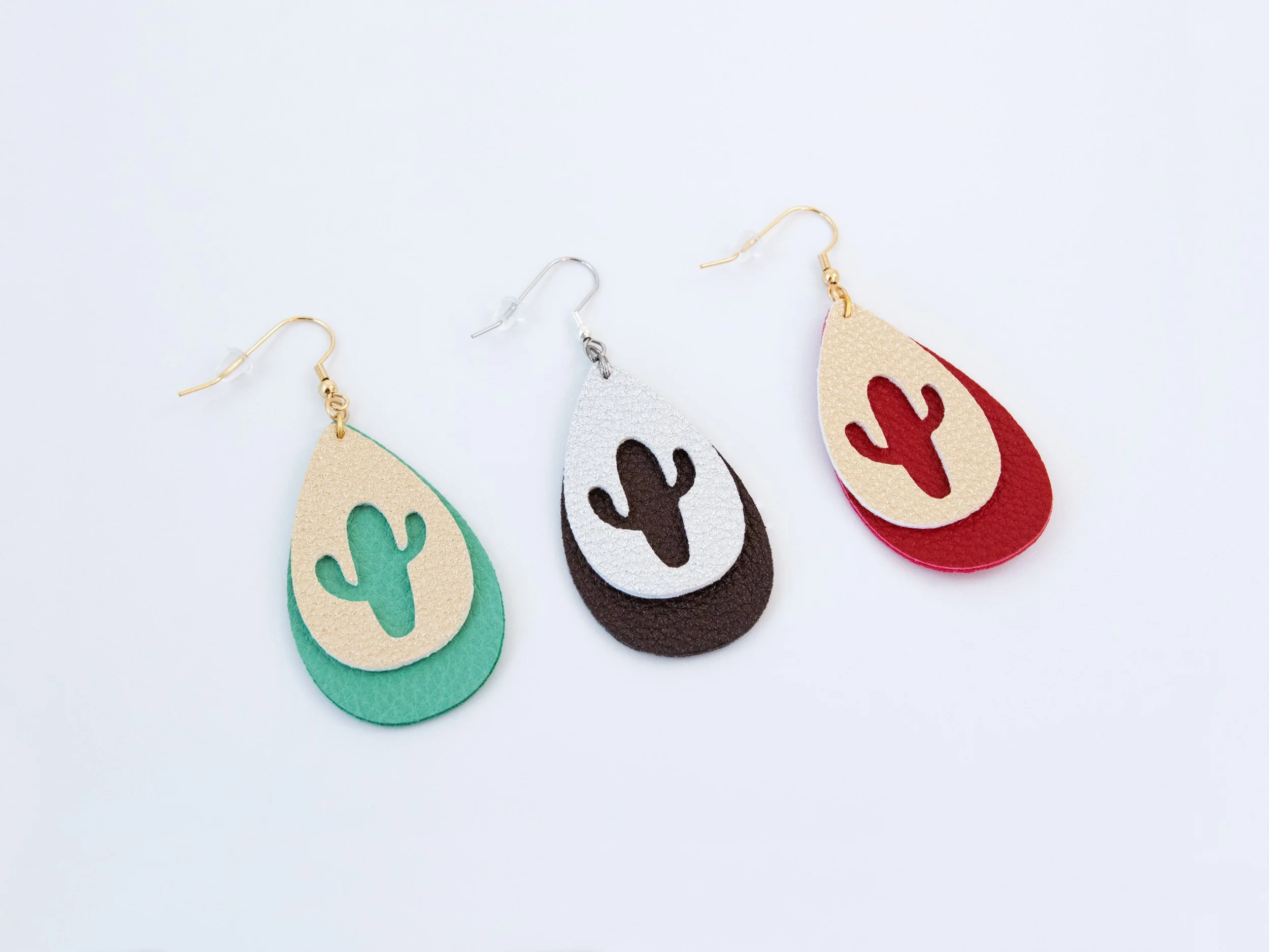 Angled view of 1 cactus teardrop earring per color option: green and gold, dark brown and silver, and red and gold