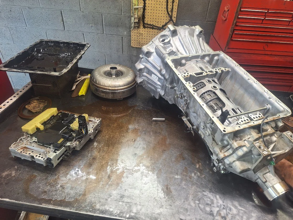 Transmission and related auto parts on a workbench in a workshop.