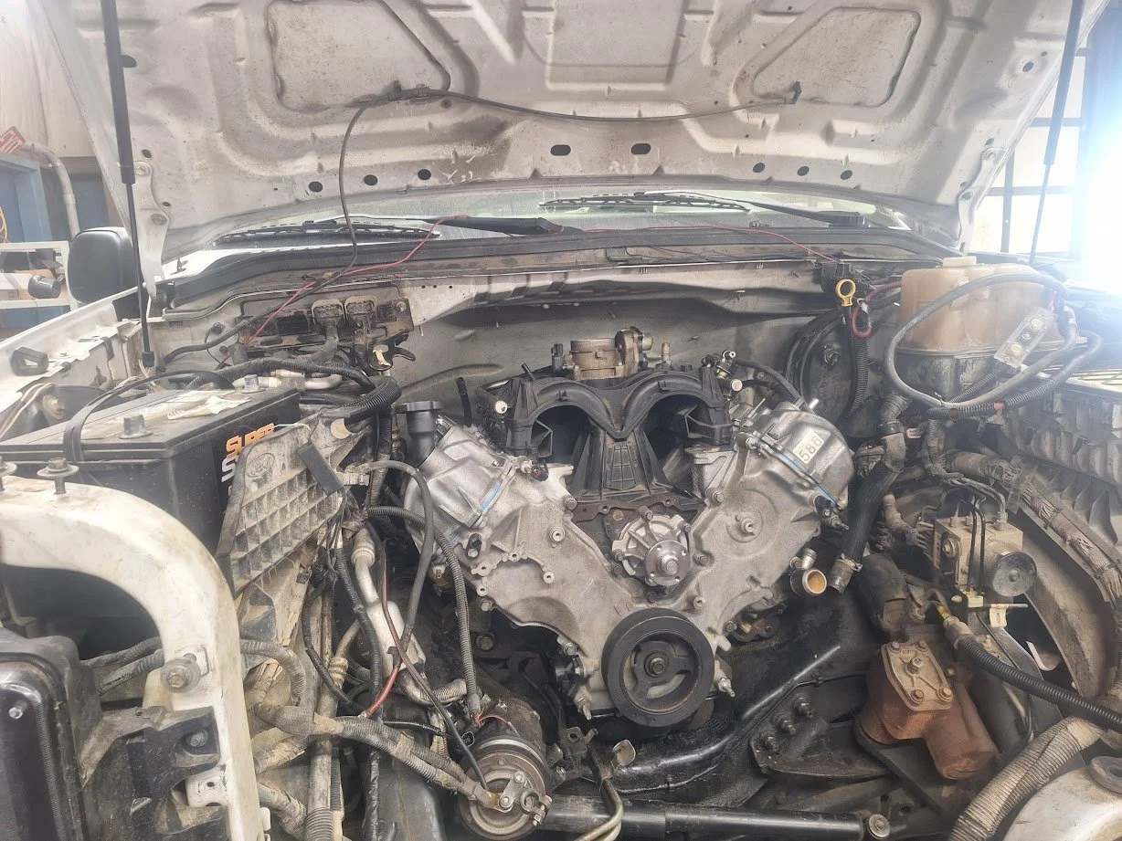 Open car hood exposing engine and surrounding components, with some wires and hoses visible.