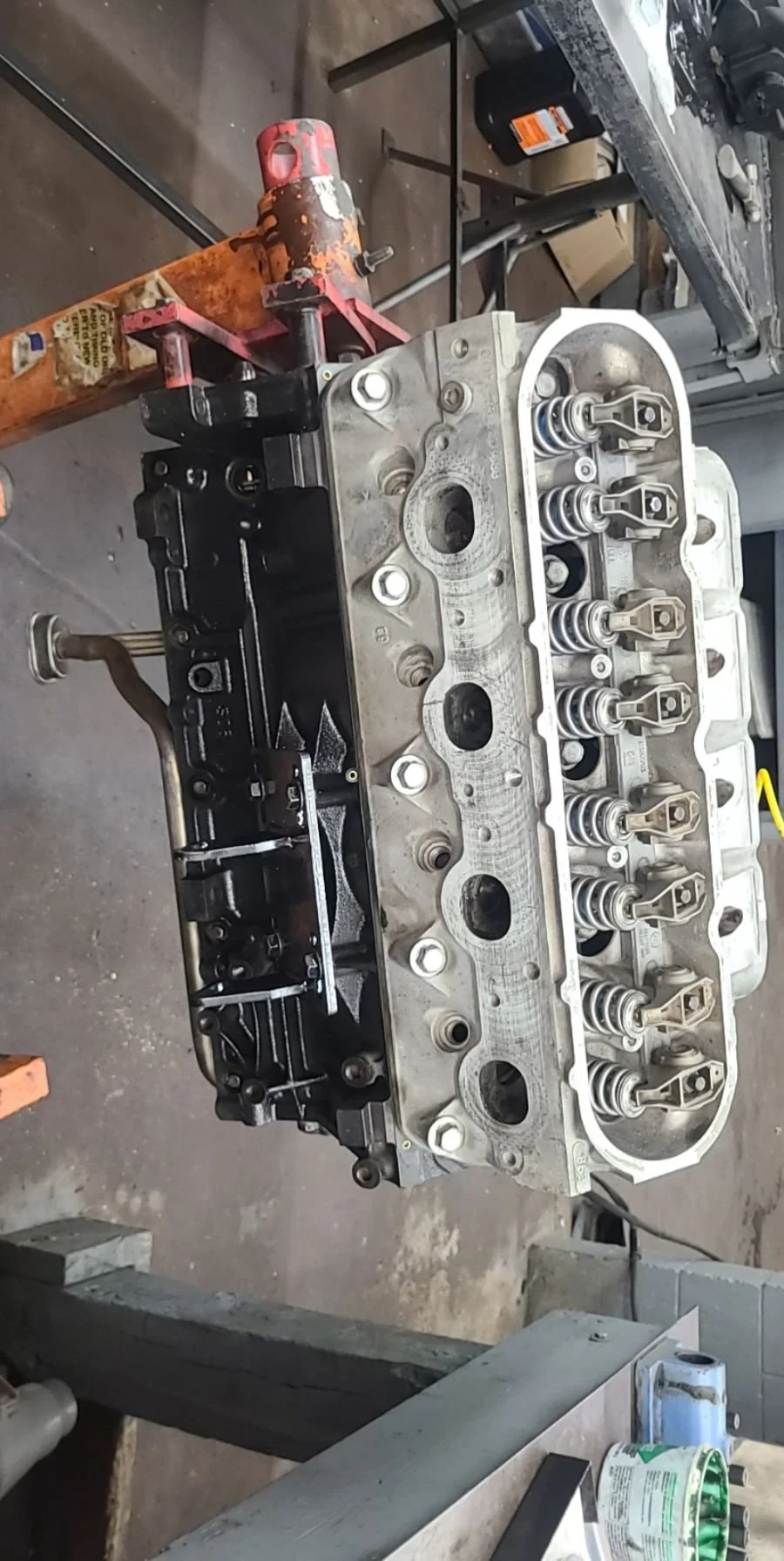 A disassembled car engine head mounted on a workbench in a workshop.