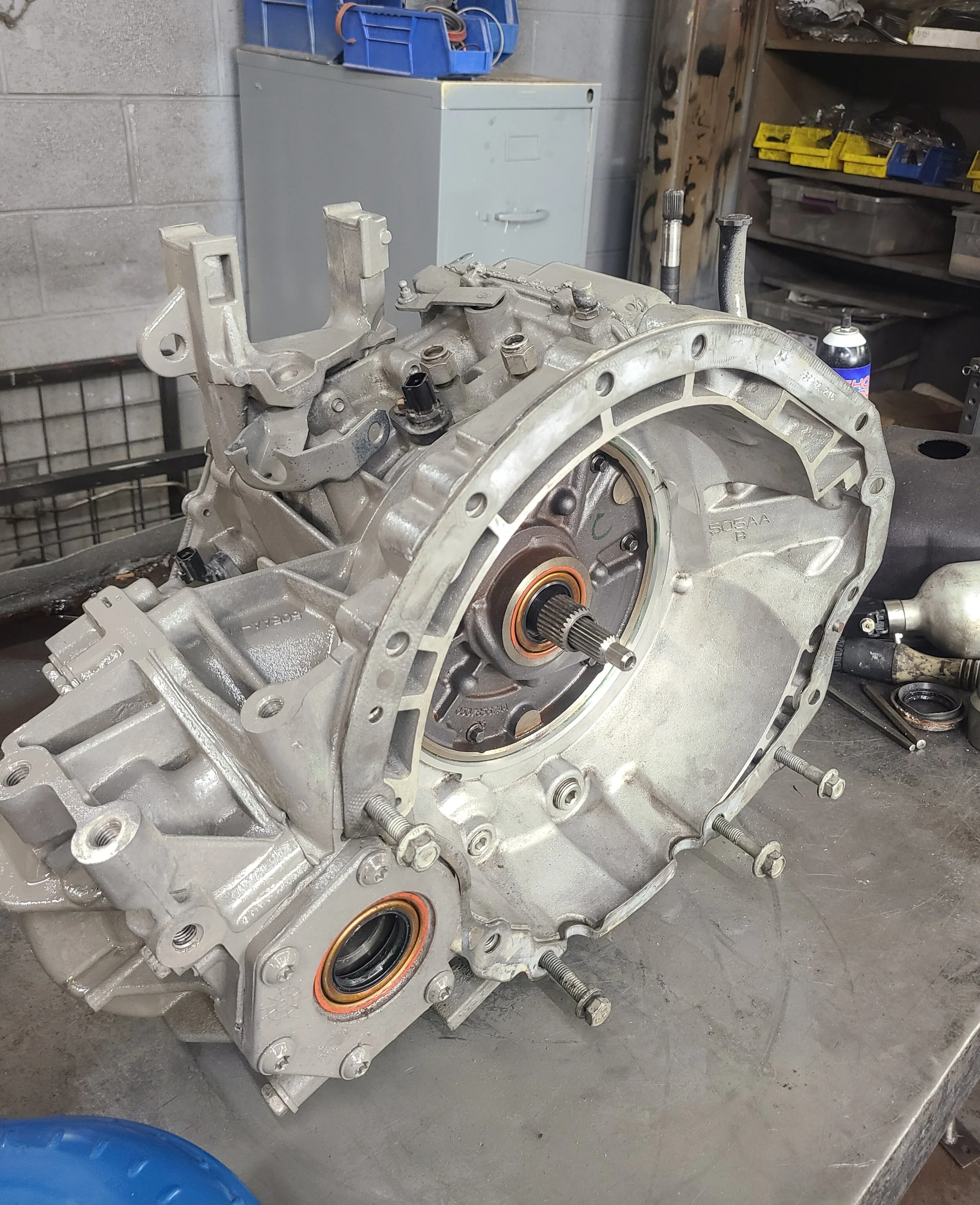 An automotive transmission housing resting on a workbench in a garage or workshop.
