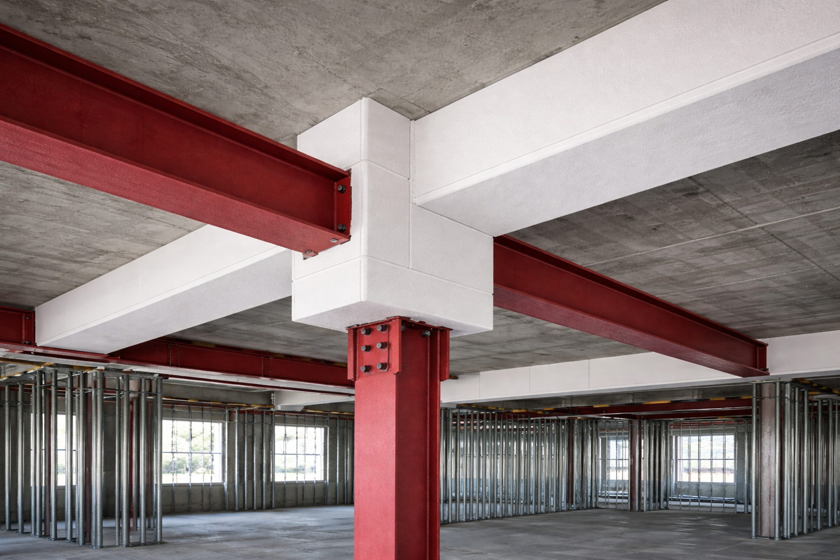 Construction interior with exposed steel beams, concrete ceiling, and metal framing.