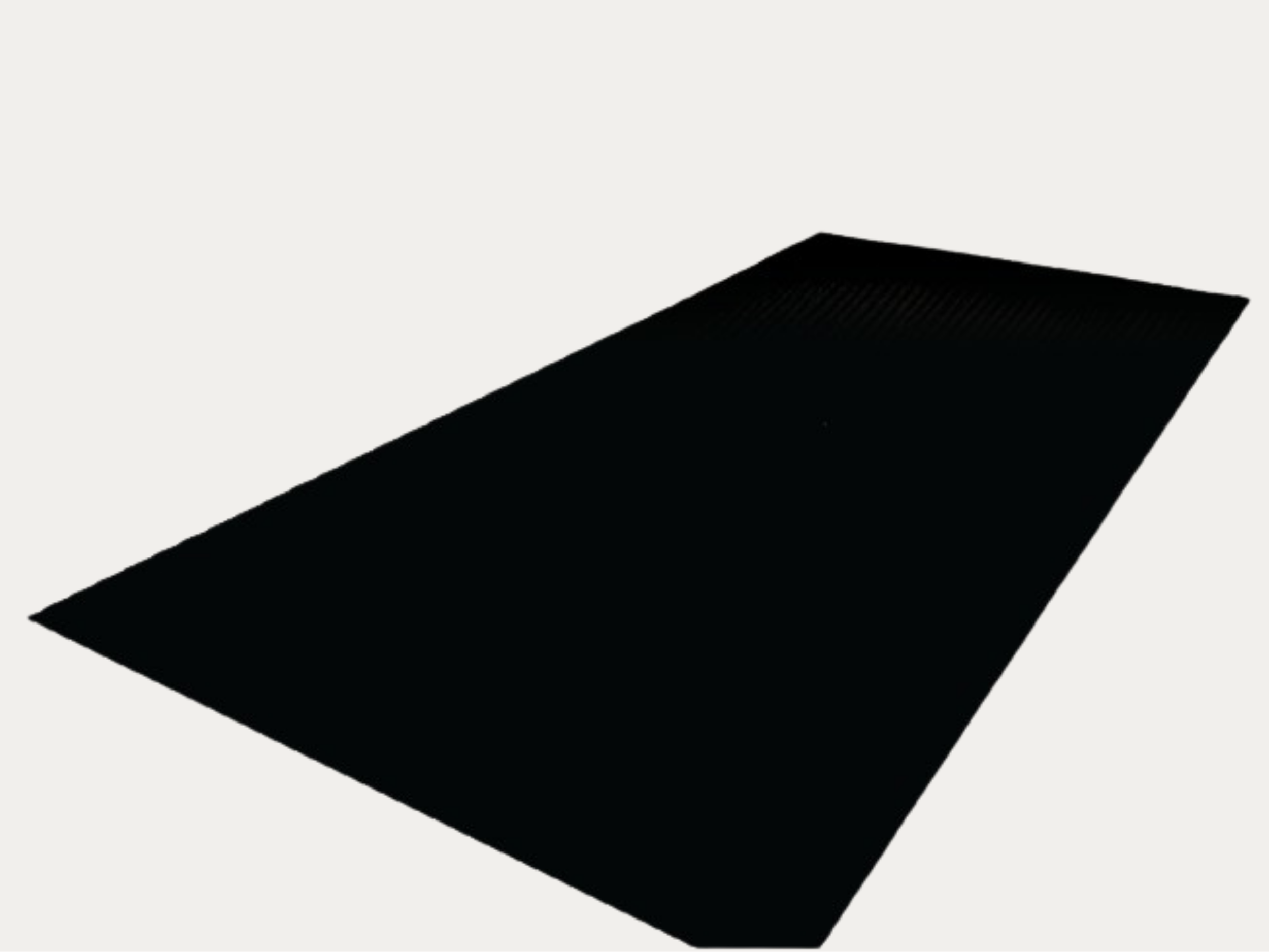A black rectangular object with textured ridges on one side, placed on a plain light-colored surface.