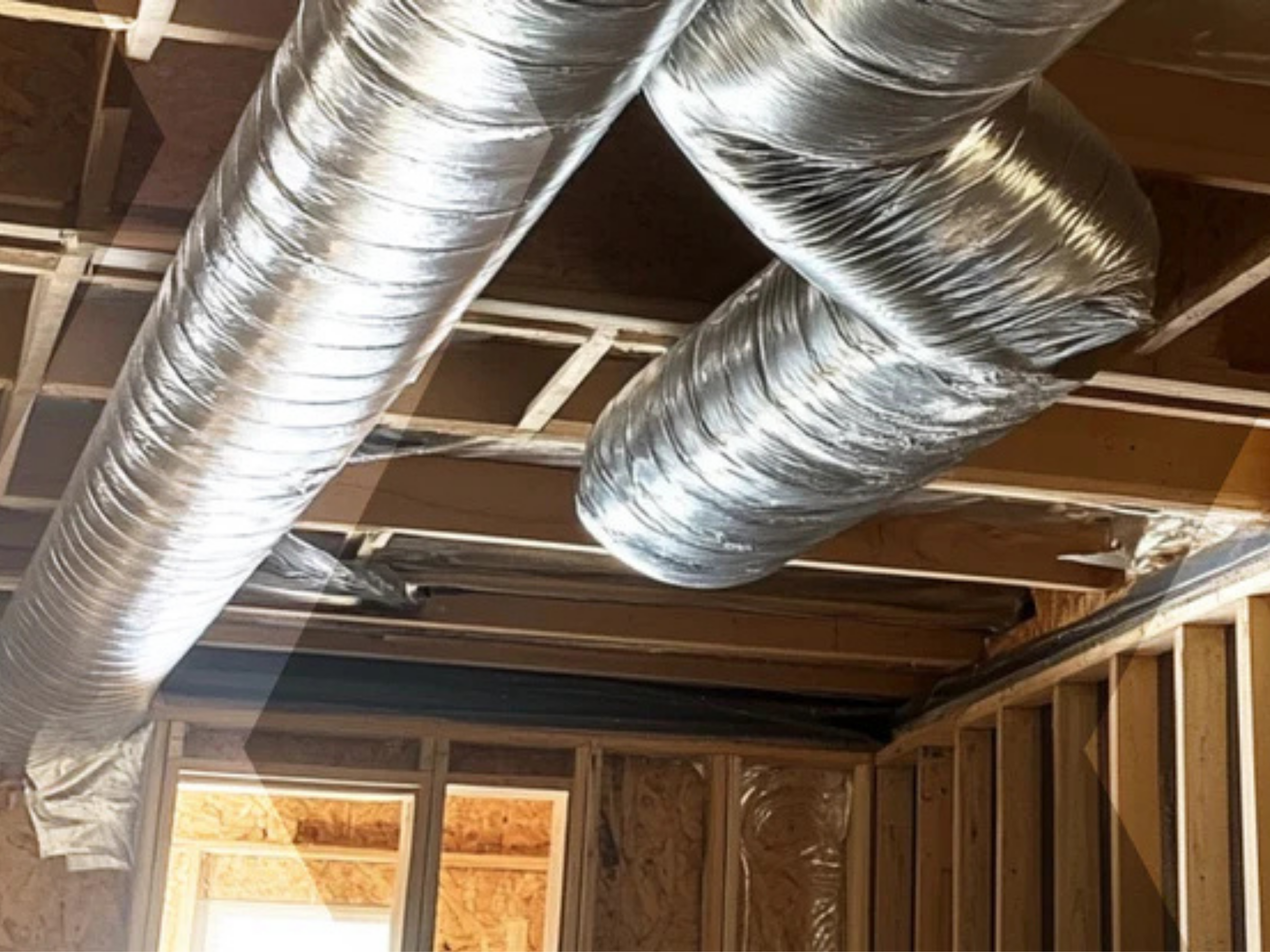 Unfinished construction room with exposed wooden framing and two shiny, flexible aluminum duct pipes attached to the ceiling.