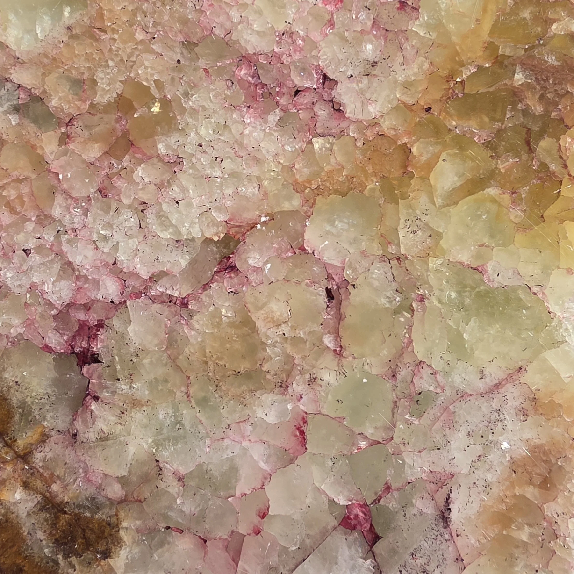 Close-up view of an Onyx stone with pink, white, and pale-yellow hues.