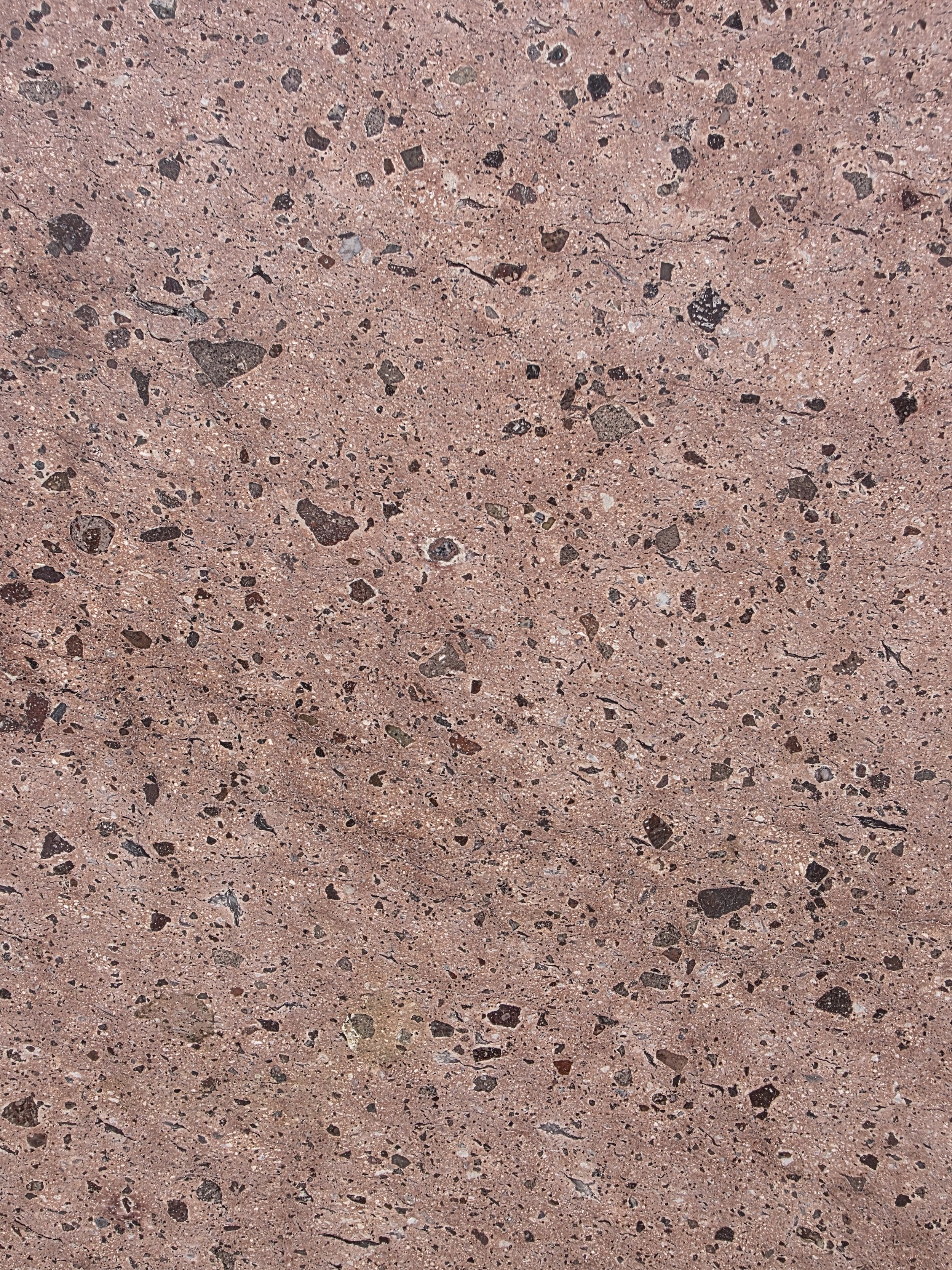 Close-up of a pink granite surface with small black, white, and green mineral flecks.