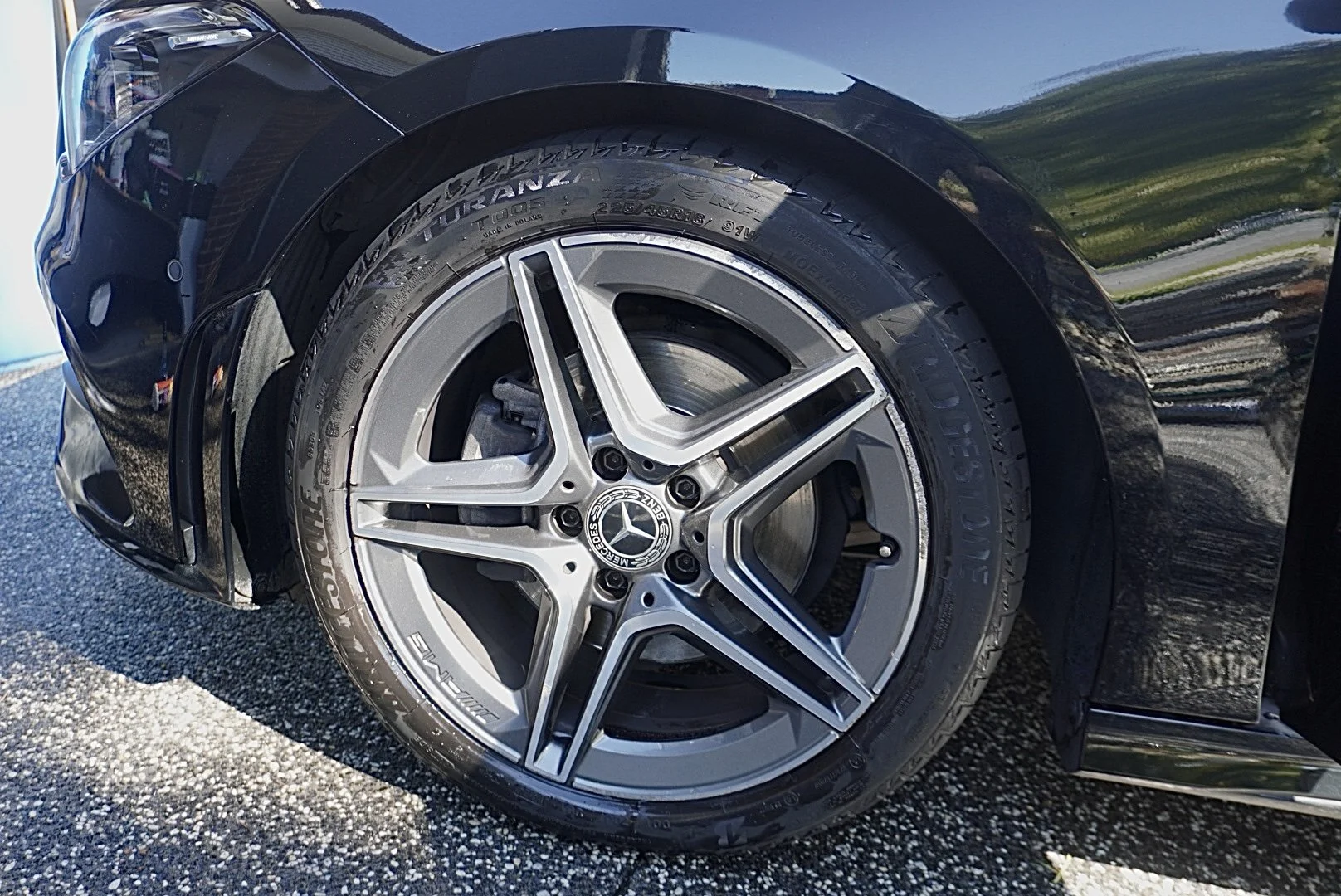 Close-up of a black Mercedes-Benz car's front wheel, showing its alloy rim with a Mercedes logo center cap and a Michelin tire.