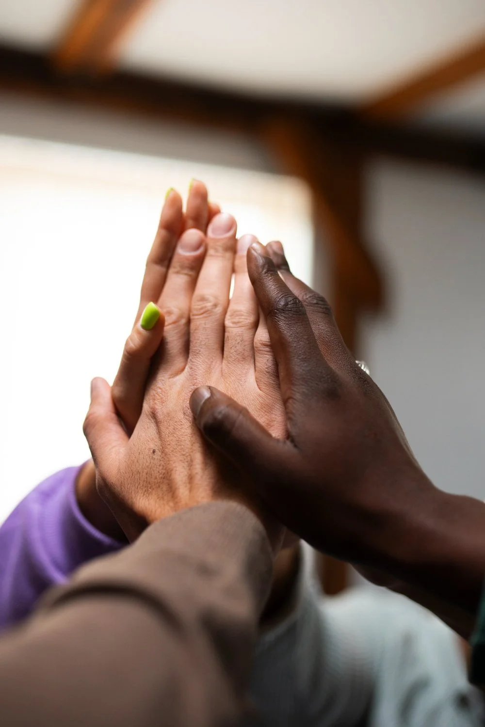 Multiple hands stacked together in a gesture of unity or support.