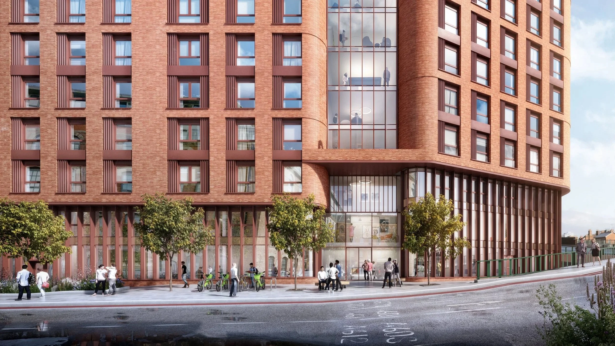 Modern brick building with glass entrance and people walking on a sidewalk