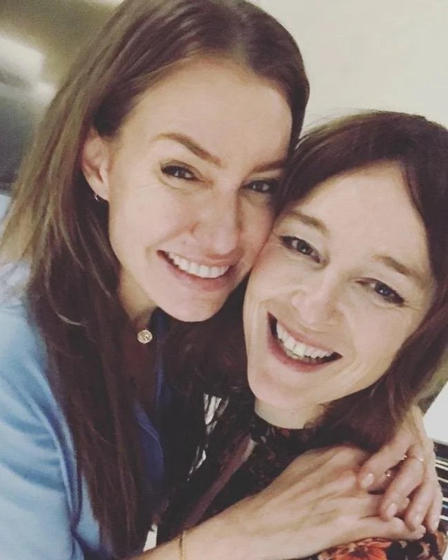 Two women smiling and hugging each other in a close-up photo.