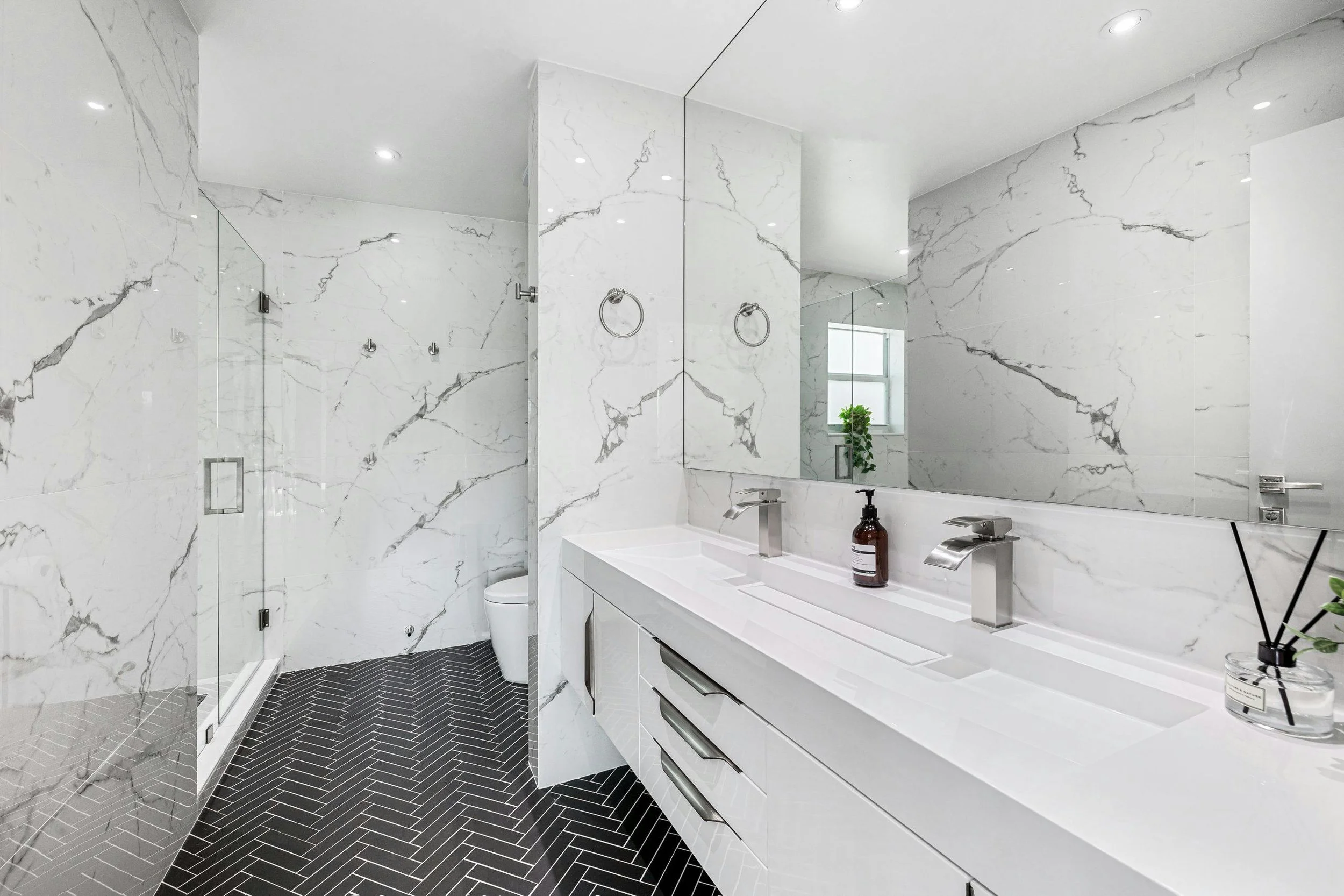 Luxury bathroom renovation with Carrara marble walls and herringbone tiles - High-end interior modernisation by MAQ Builders.