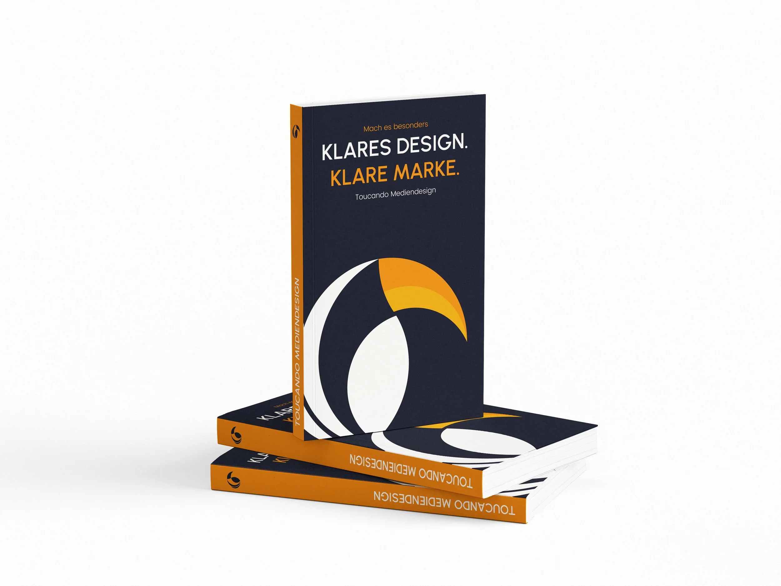 Drei Bücherstapel mit dem Titel 'Klares Design. Klare Marke.' von Toucando Mediendesign, mit blauer, weißer und oranger Farbgestaltung, liegend auf weißem Hintergrund.