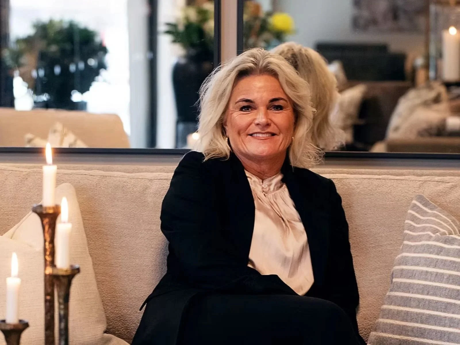 En smilende innehaver av bedriften som sitter i showroom. Ellen Hagen skaper varme og en god atmosfære i alle rom.