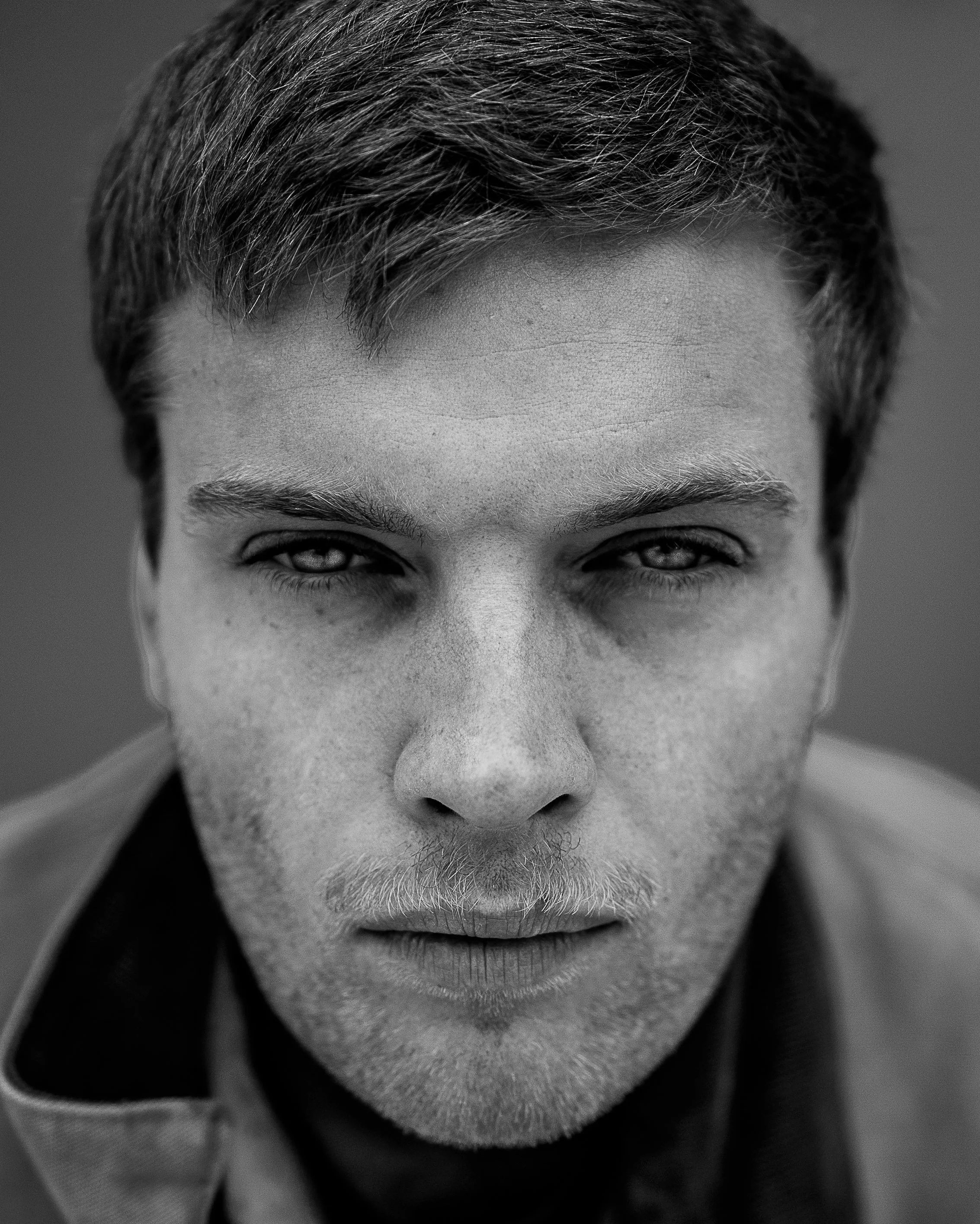 Close-up black and white photograph of a young man with intense expression and direct gaze.