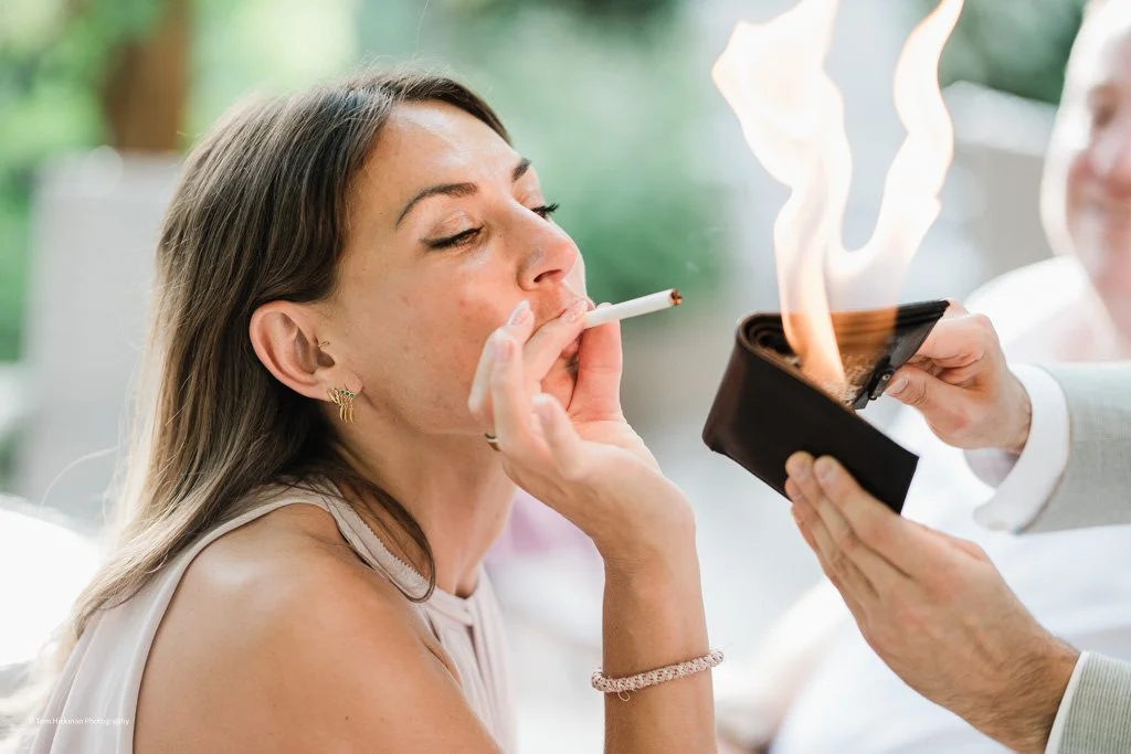 A woman is smoking a cigarette while someone holds a lighter close to it, creating a flame and smoke.