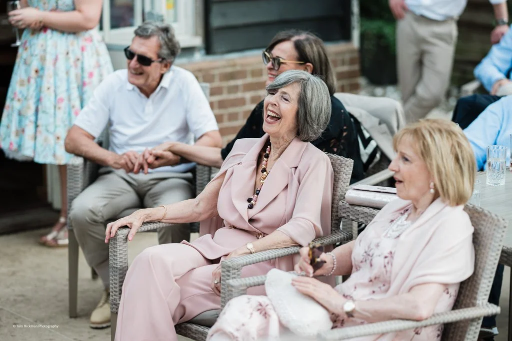 Group of people laughing and chatting outdoors at a social gathering.