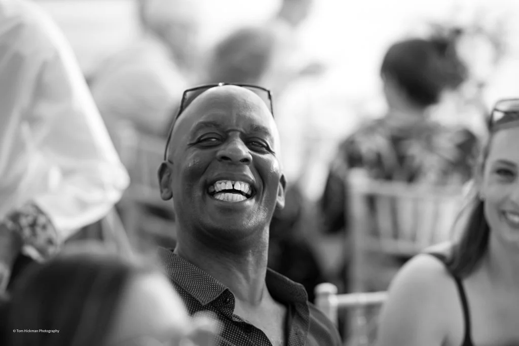 Smile of a man with glasses on his head, in a group of people at an outdoor event, black and white photo.