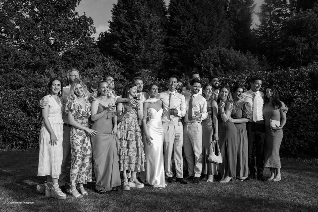 A group of people dressed in formal attire standing together outdoors, smiling and posing for a photo.