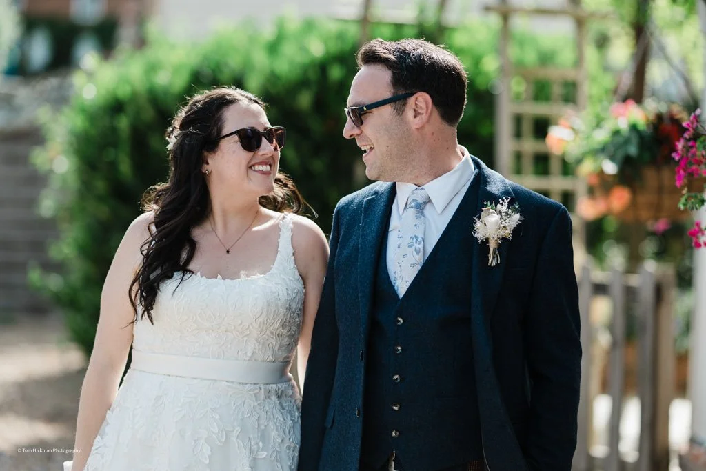 A smiling bride and groom looking at each other outdoors during their wedding.