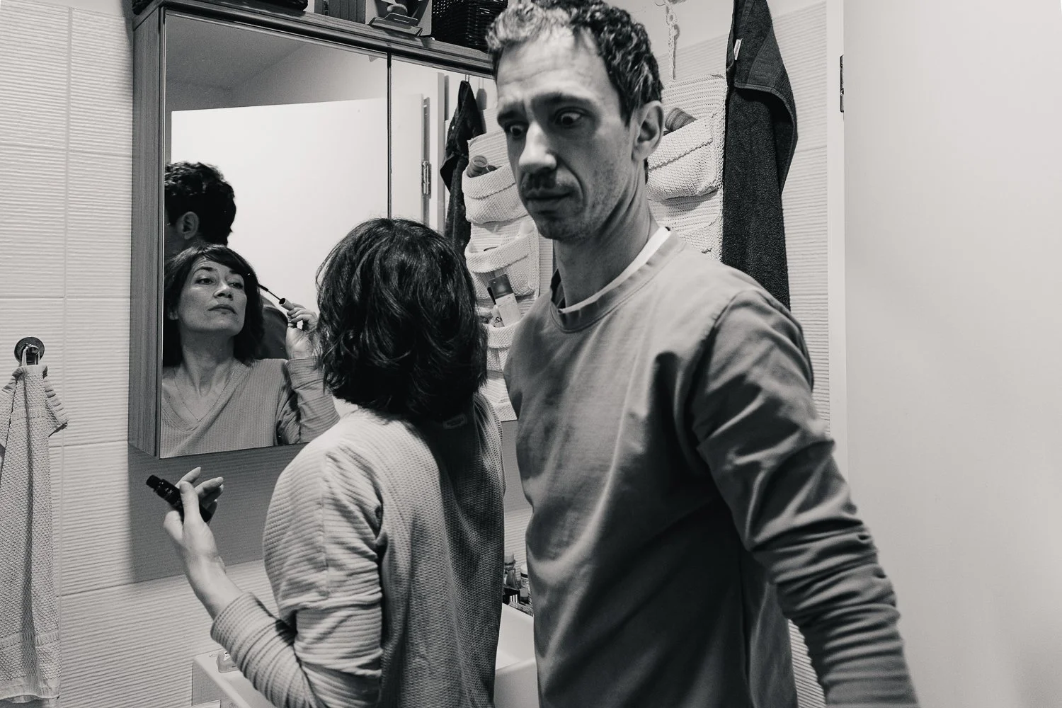 družinsko fotografiranje mama se ureja preg ogledalo in oče čudno gleda fotografija je črno bela