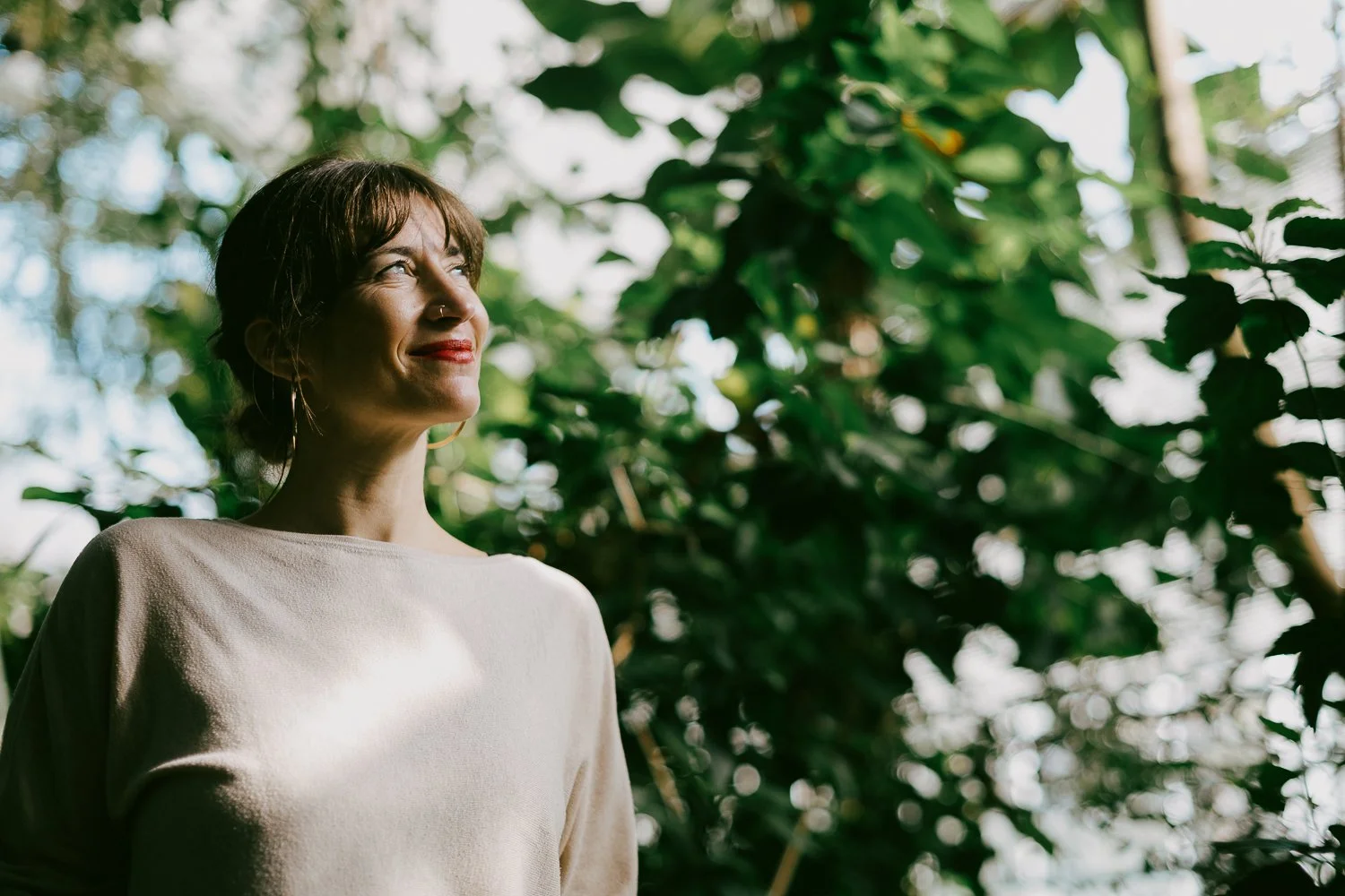 Zadovoljna ženska z rdečo šminko na ustnicah v botaničnbem vrtu. 