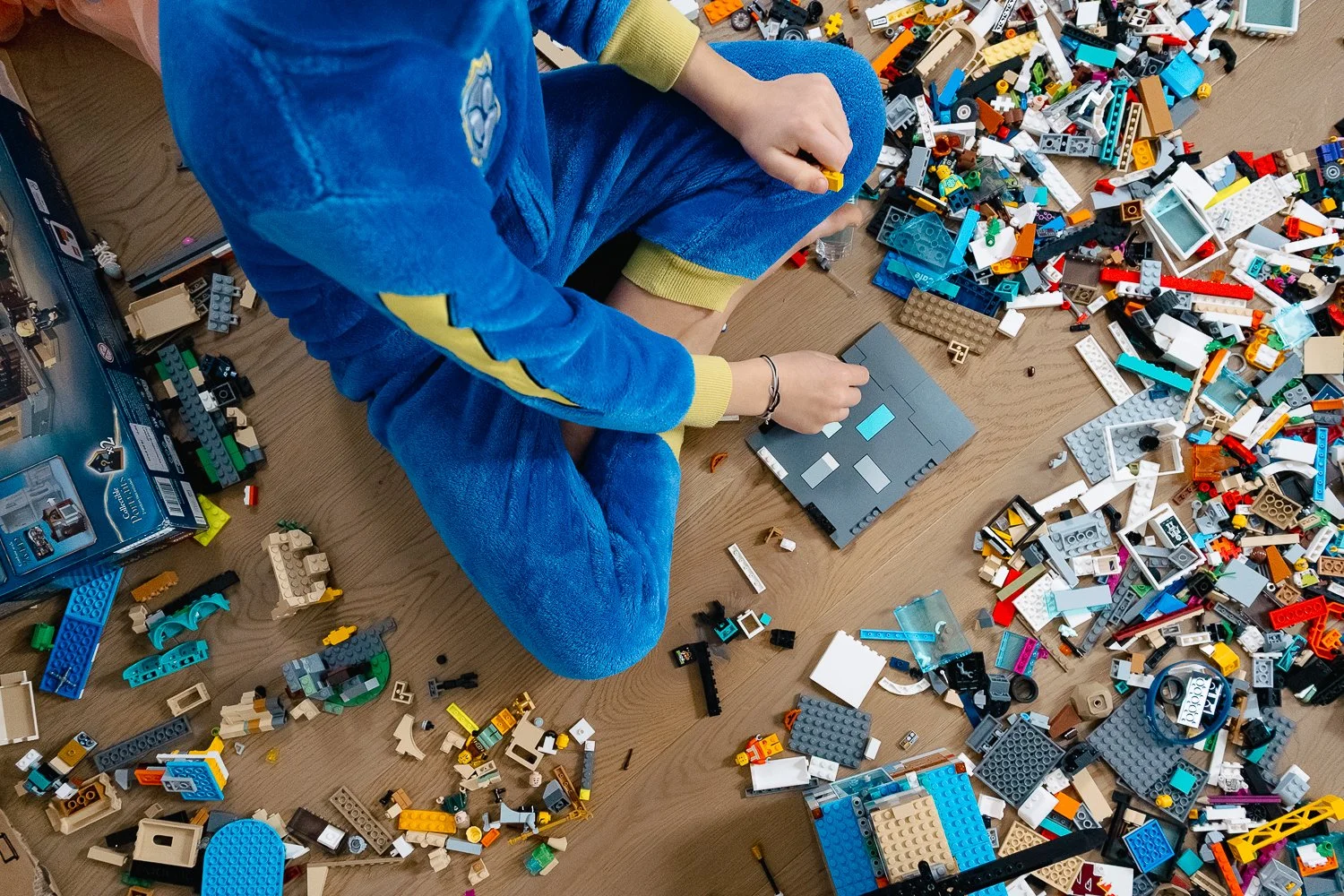 družinsko fotografiranje otrok v pajacu tačke na patrulji sedi na tleh v sobi polni lego kock in sestavlja cesto