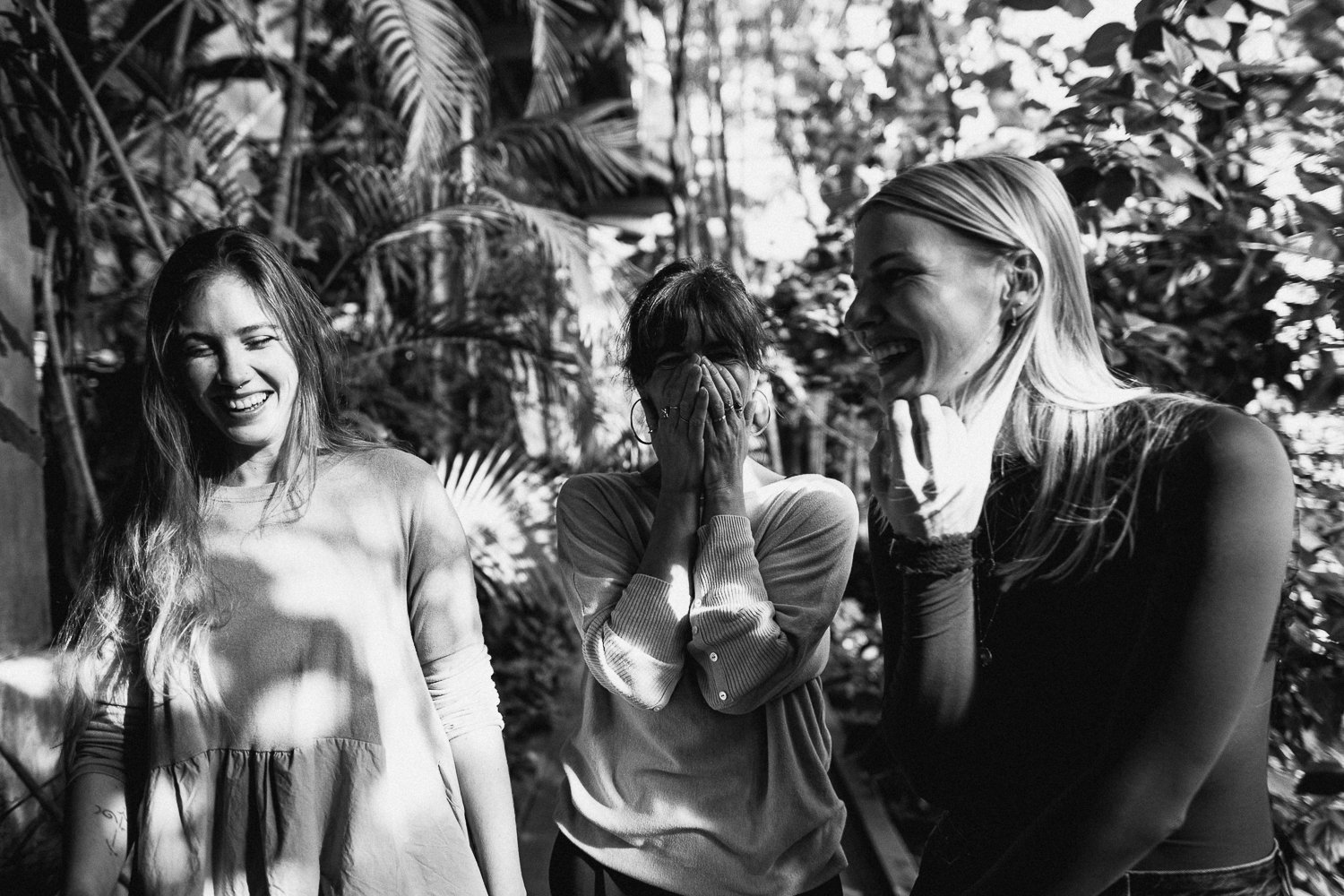 tri mlade ženske ki se smejijo med drevesi