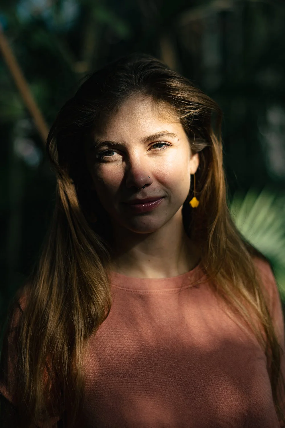 Ženska obsijana s soncem v roza poluverju z naravnim make-upom v botaničnem vrtu. 