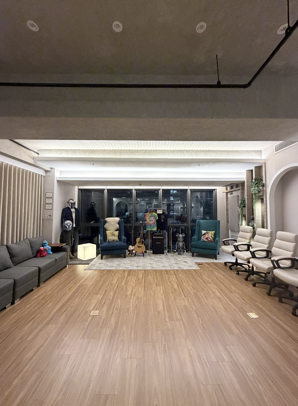 Empty waiting room or lounge with chairs on the right, sofas on the left, and musical instruments, plush toys, and decorative objects at the back.