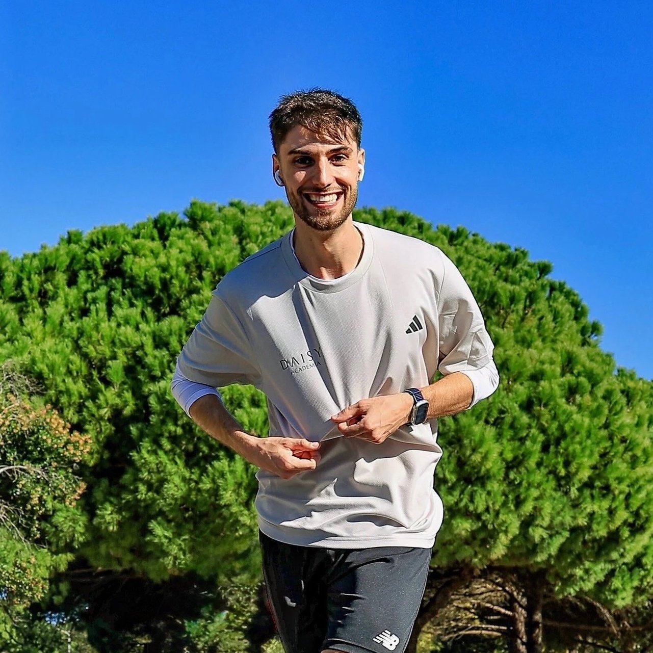 Homem correndo ao ar livre com fundo de árvores verdes e céu azul