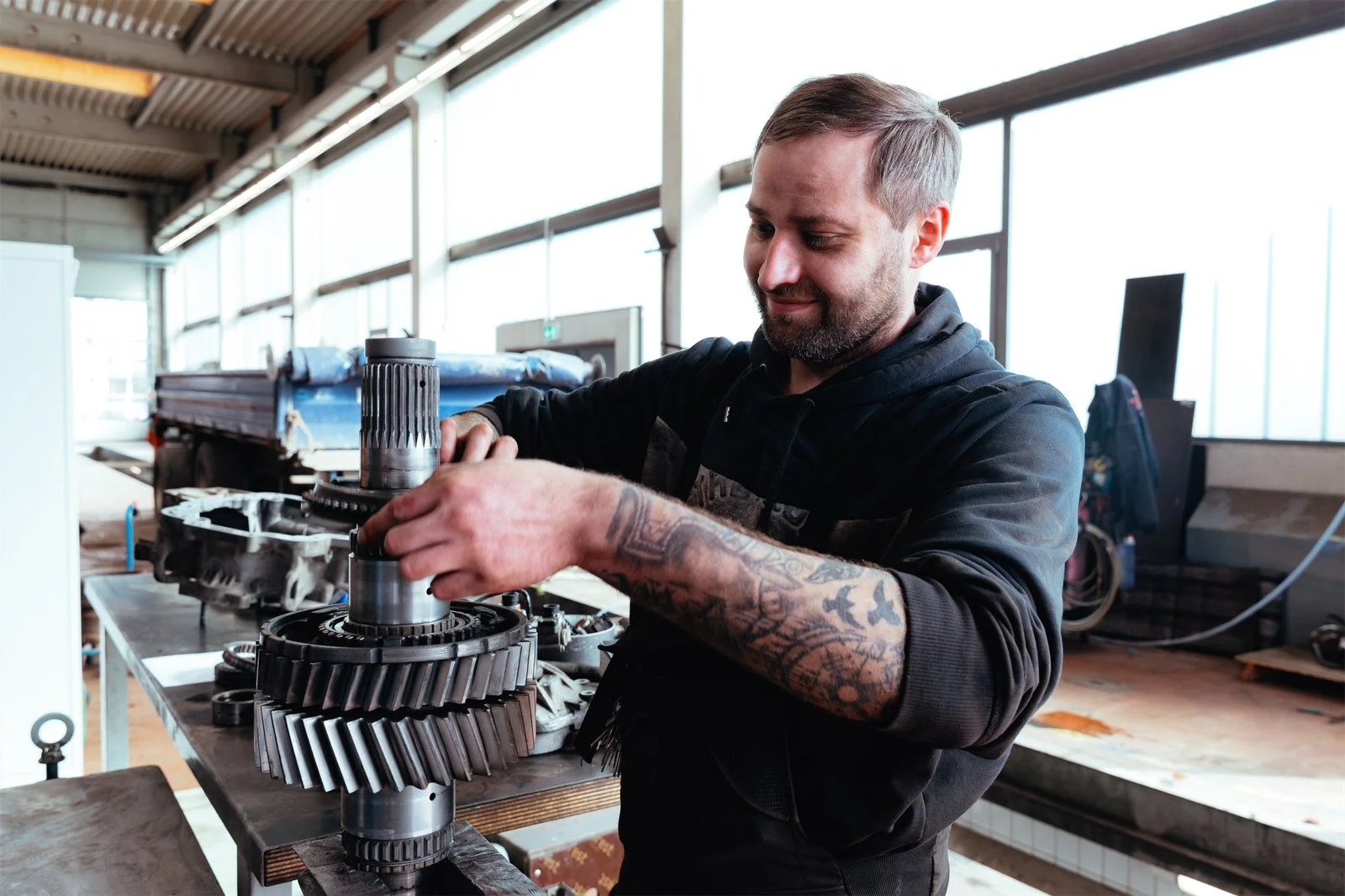 Mann arbeitet an Getriebeteilen in einer Werkstatt.
