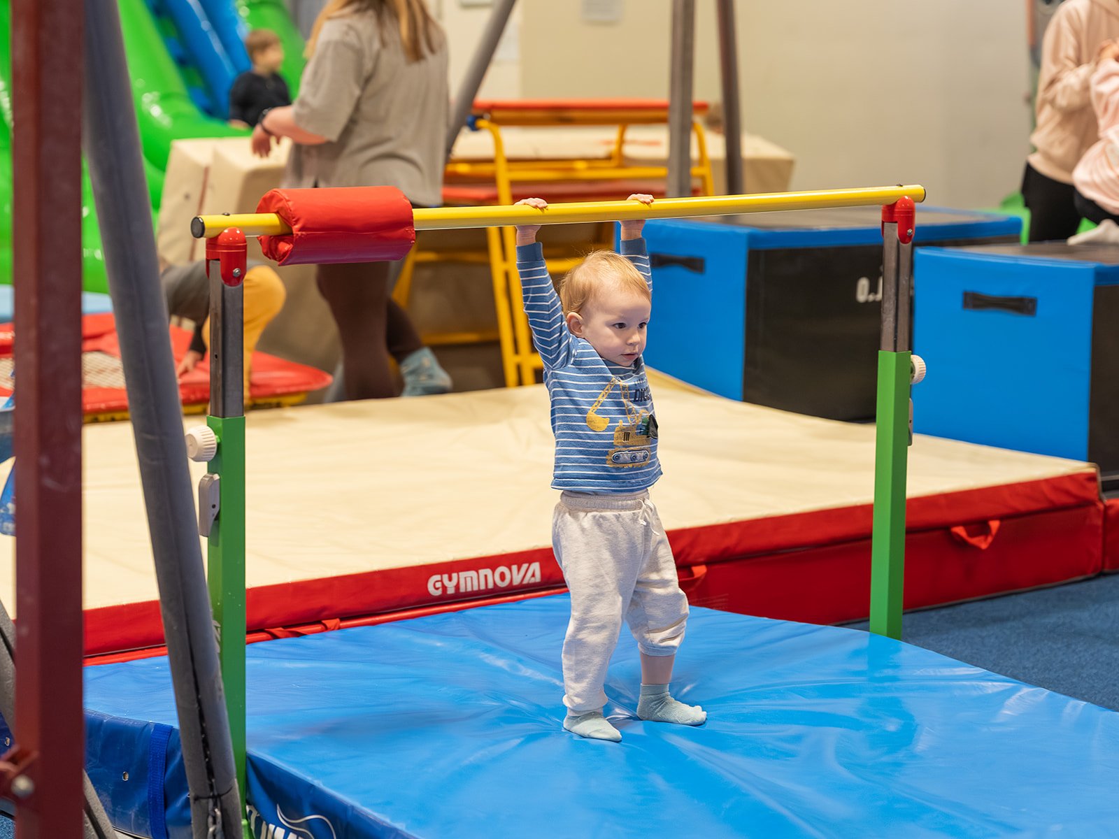 Child in a striped outfit inside a play area with netting.