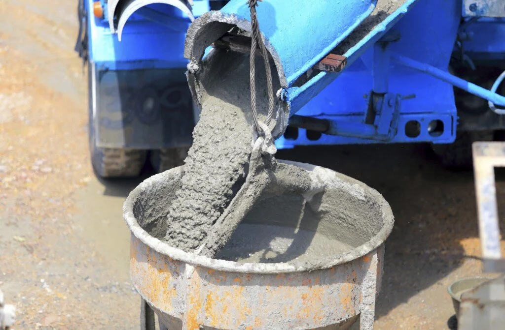 Concrete being poured from a chute into a mixer.