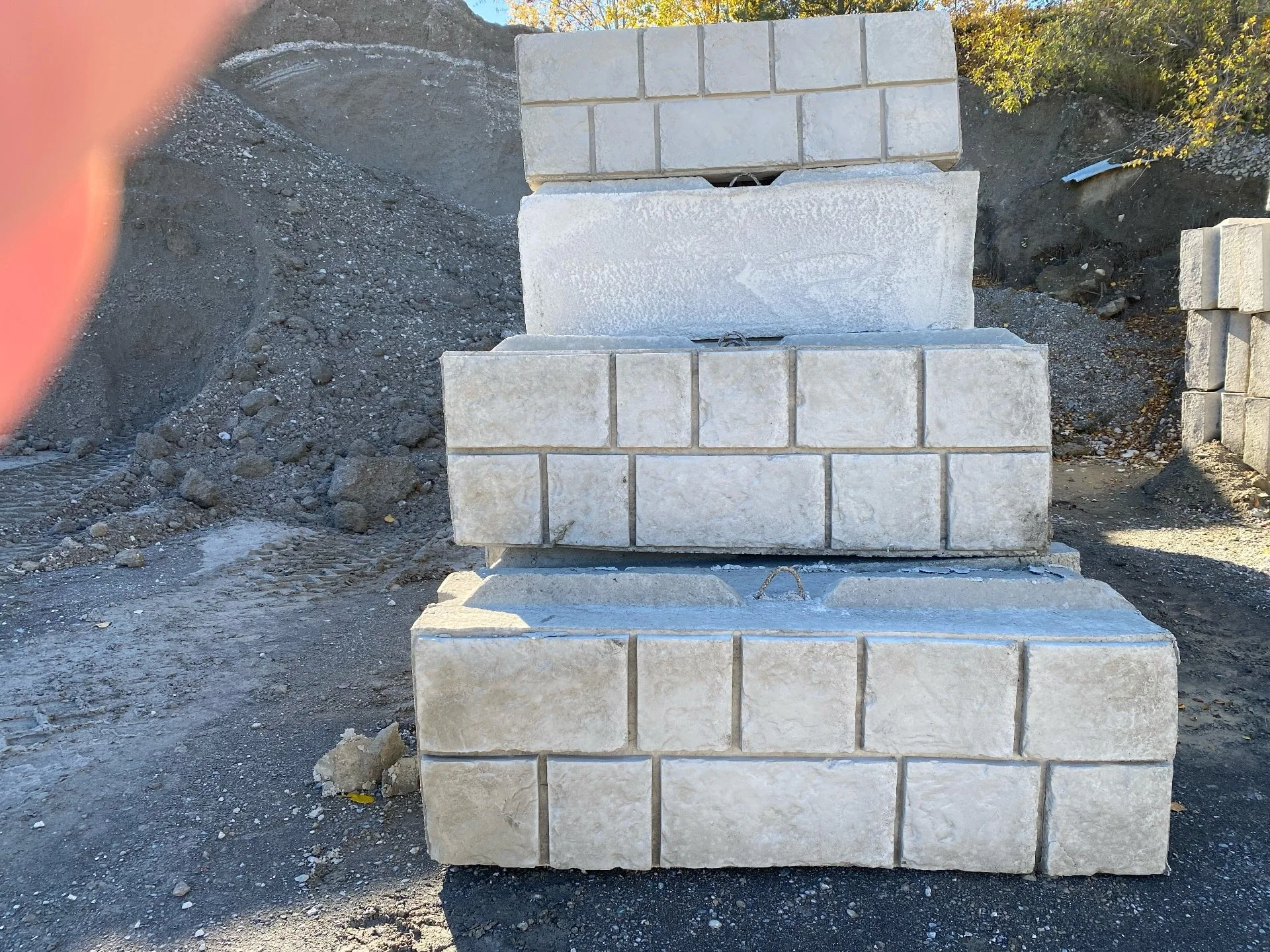 Stacked concrete bricks or blocks on a construction site with dirt and gravel in background.