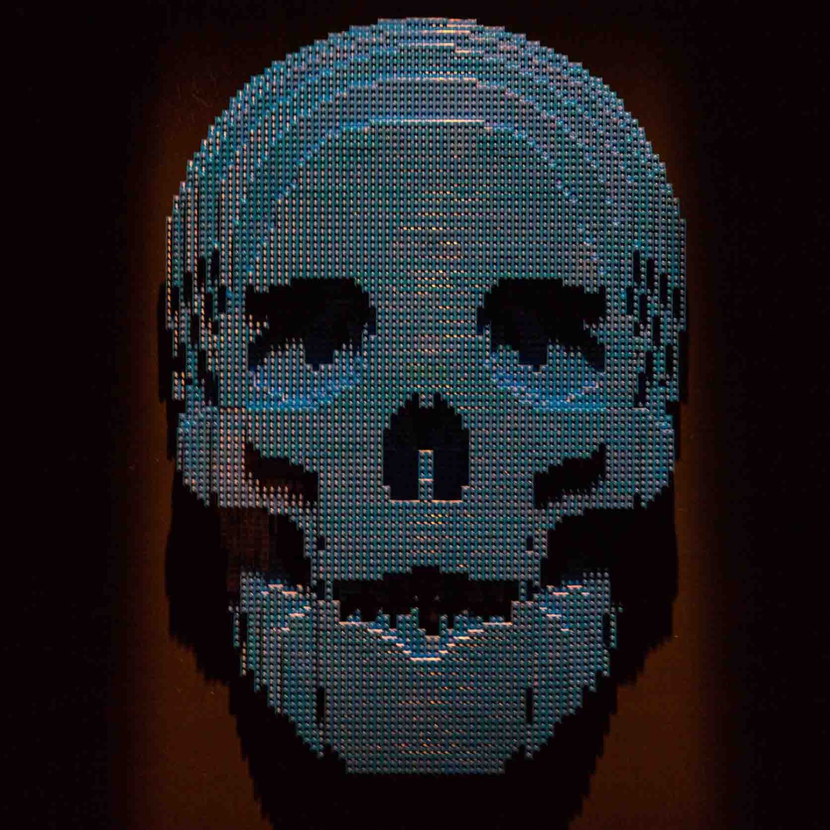 A large skull made of colorful LEGO bricks against a dark background.