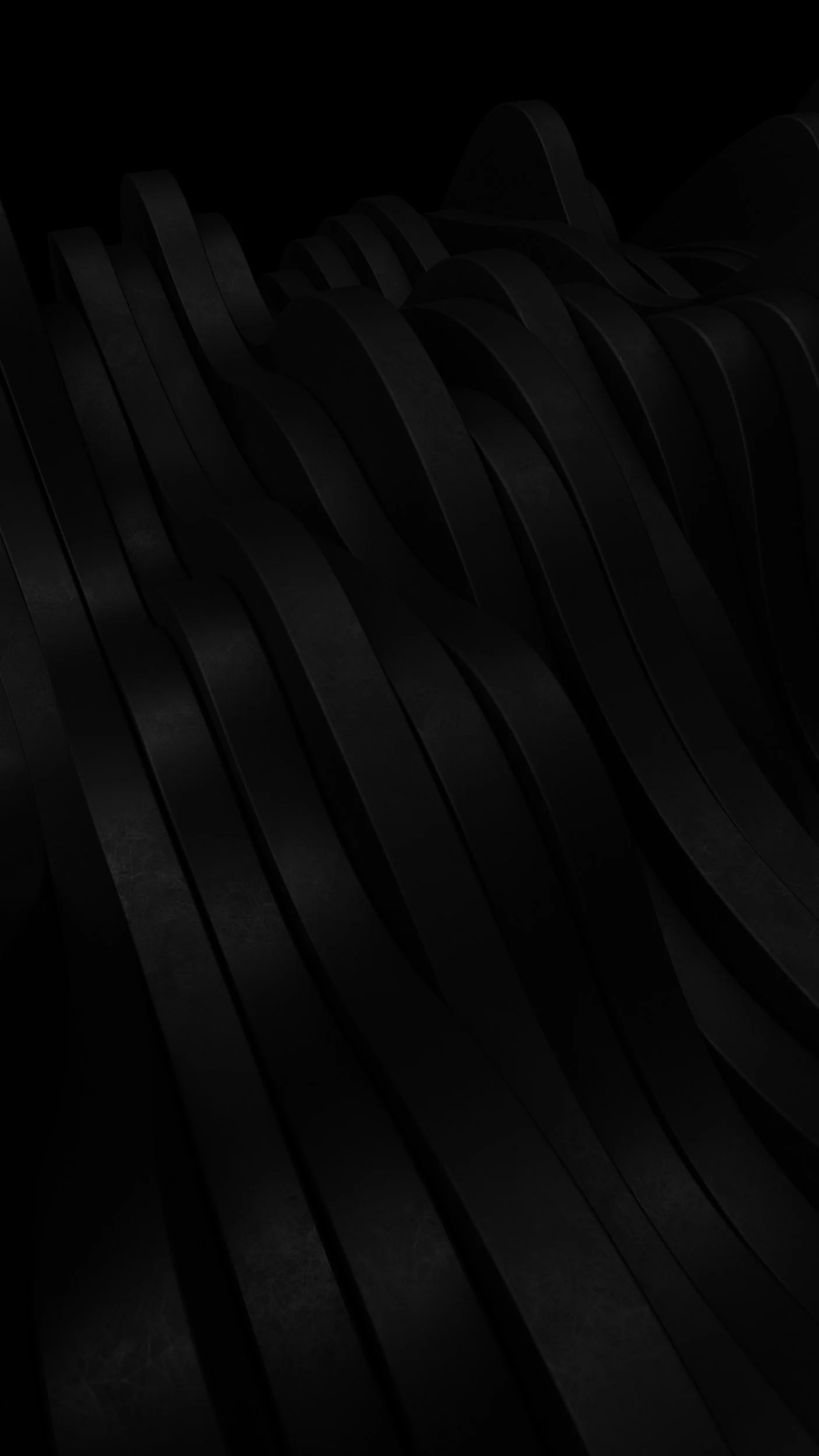 Close-up of a black, textured, abstract sculpture or object with smooth, wavy lines in low light.