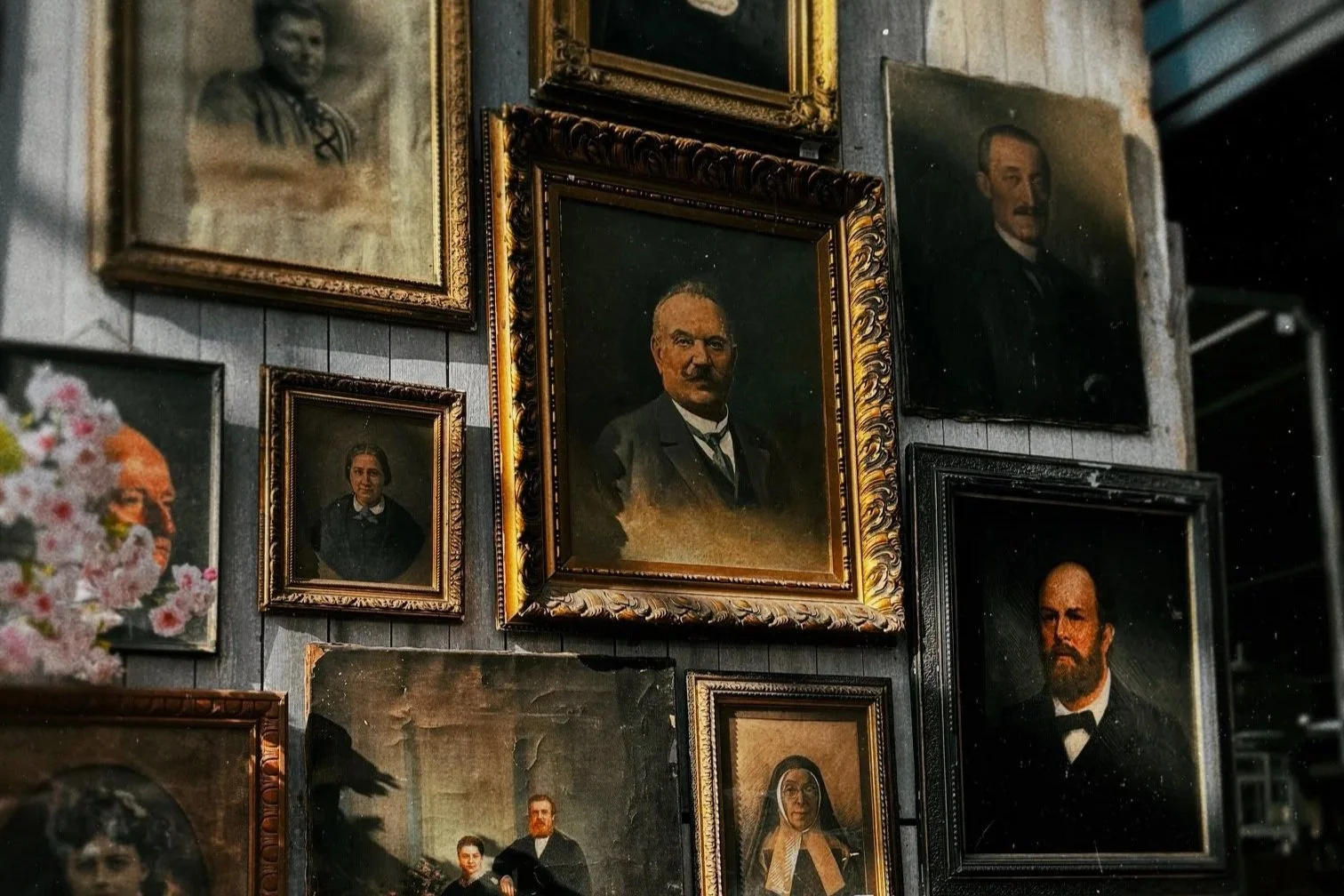 Collection of vintage framed portraits of historical figures on a wall.
