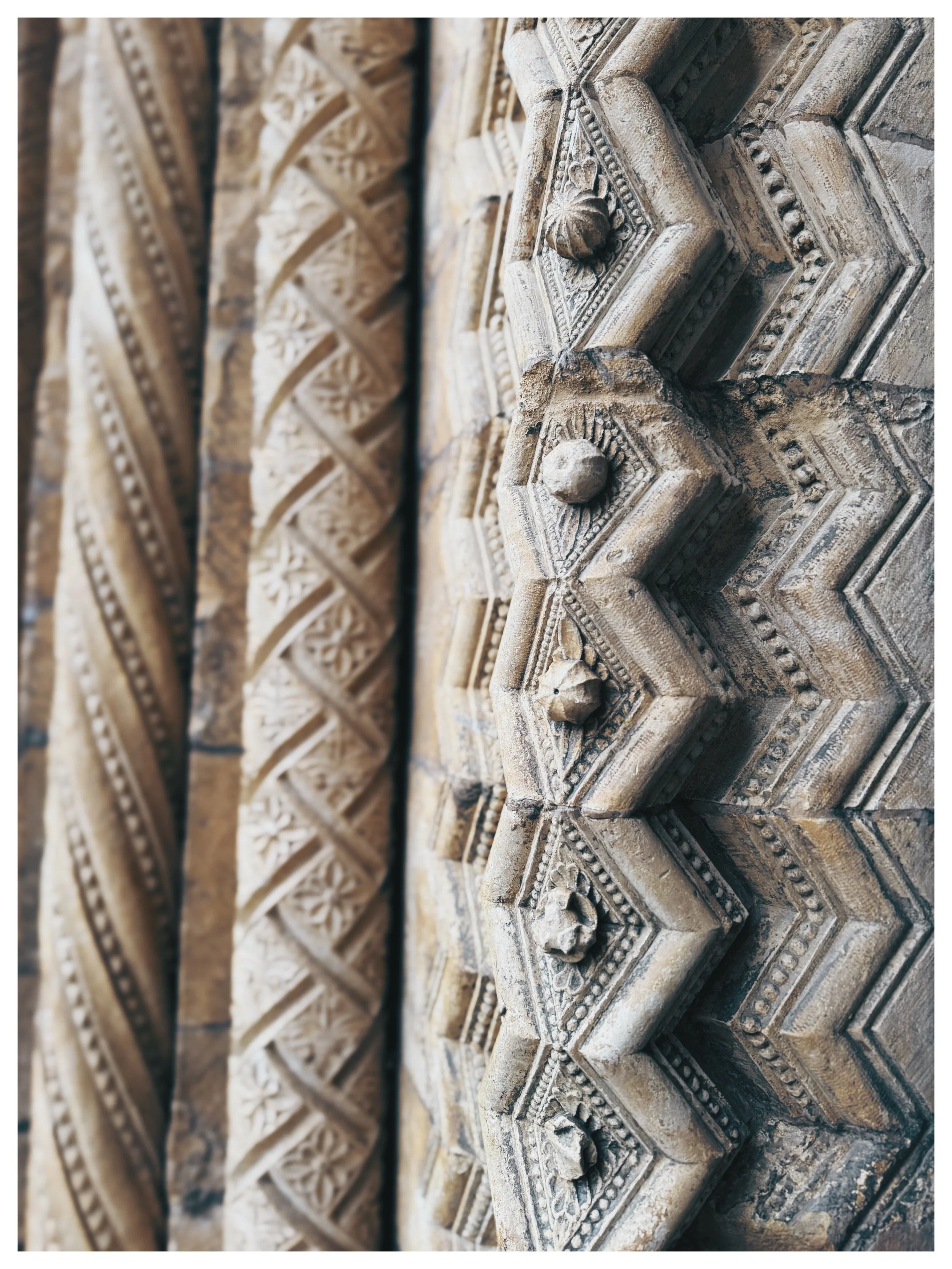 Close-up of ornate carved stone or wood architectural details in a historical building, with intricate patterns and floral motifs.