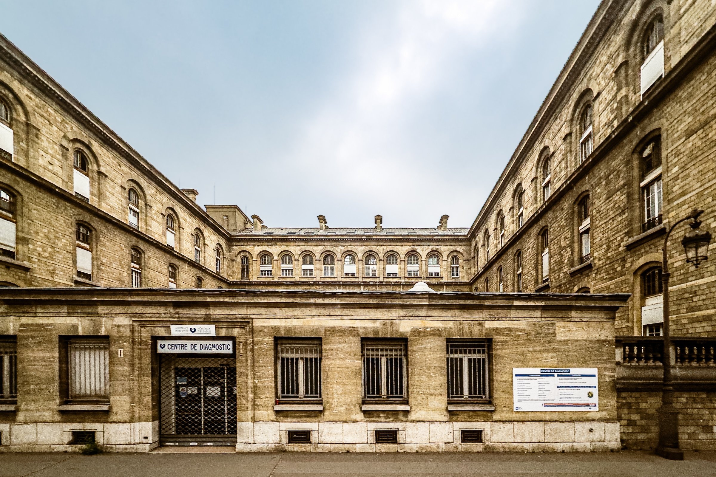 A courtyard surrounded by old stone buildings with arched windows and brick walls, and a sign indicating a diagnostic center.