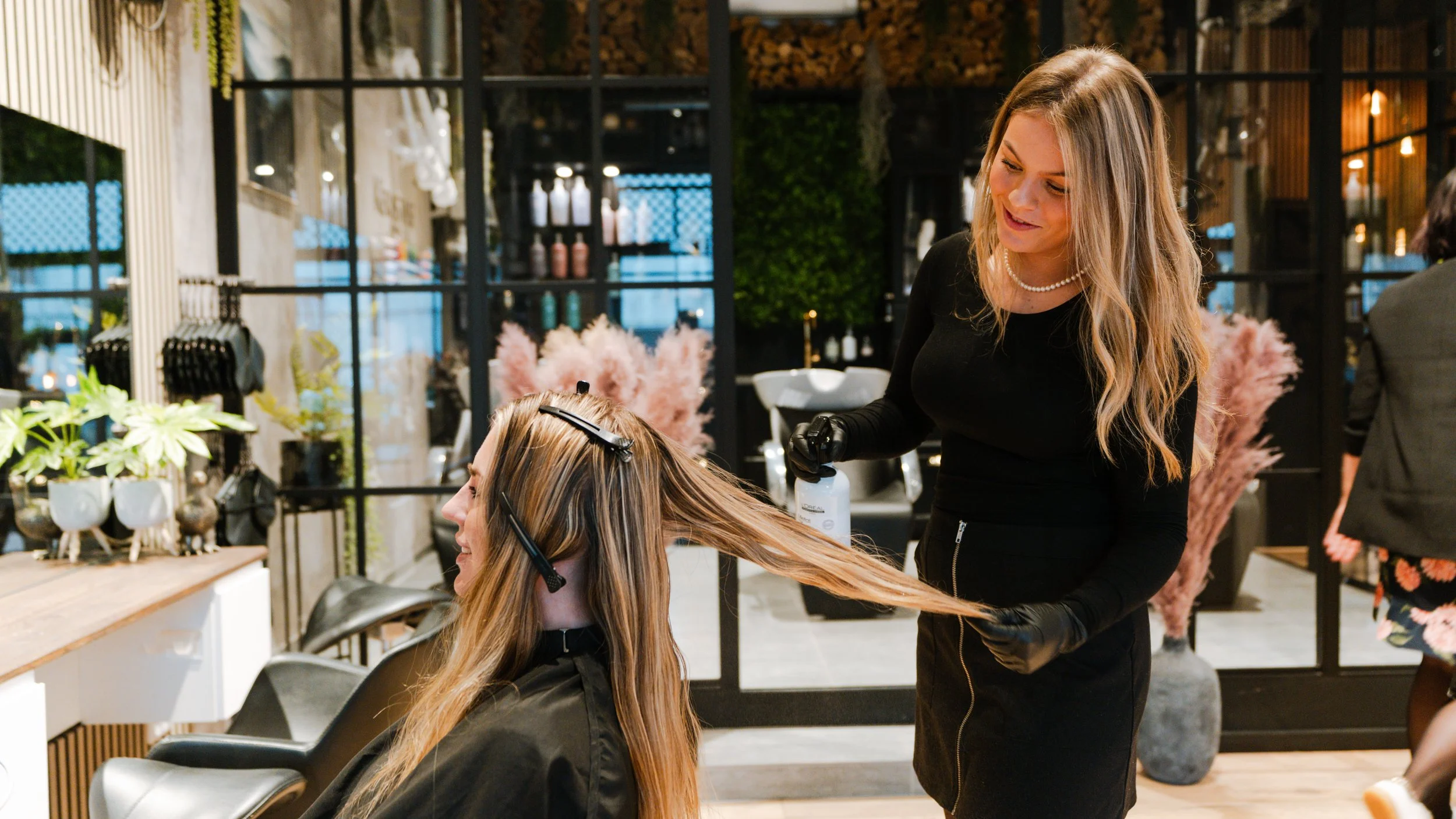 En frisør farver en kvindes hår i en frisørsalon.