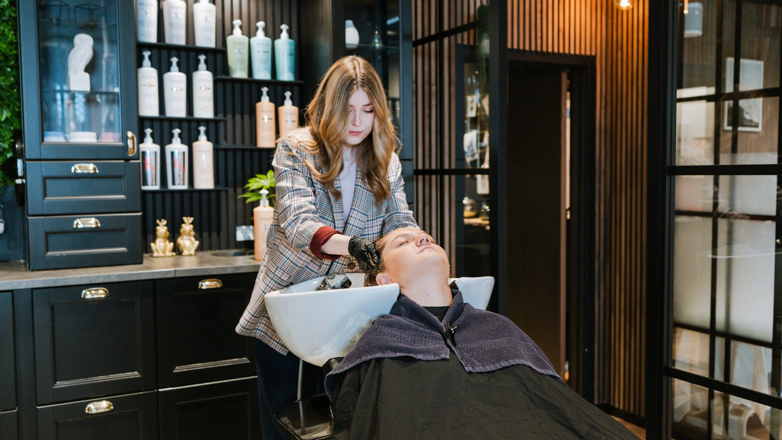 En kvinde får sin hårvask på en frisørsalon af en frisør.