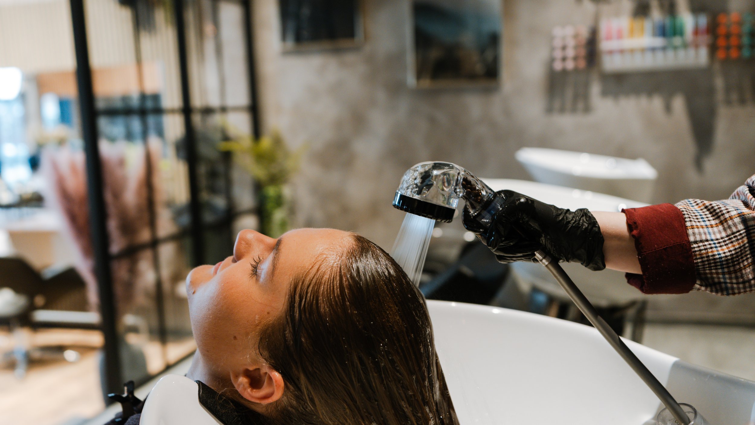 En person får vasket sit hår ved en hårvaskestol i en frisørsalon.