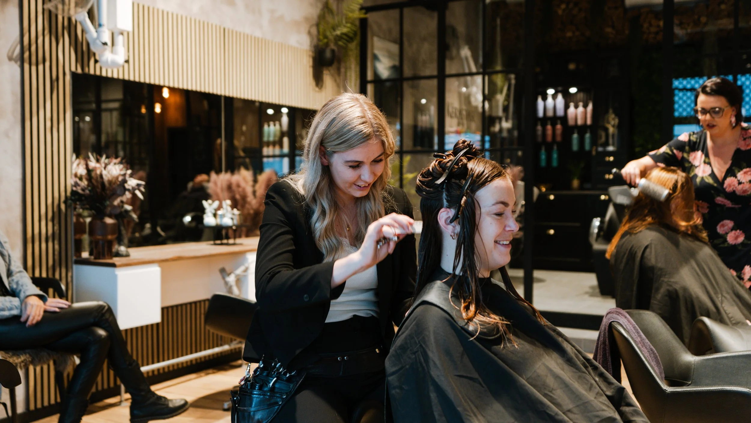 En frisør, der klipper en kvindes hår i en moderne salon.