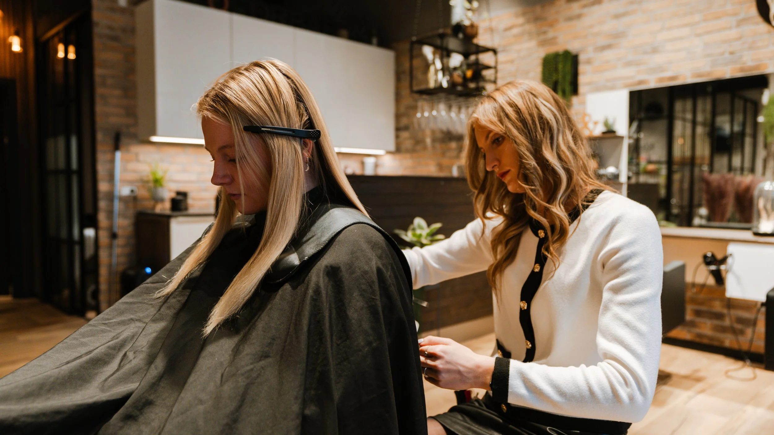 En frisør hjælper en kunde med at få en klipning i en moderne frisørsalon.