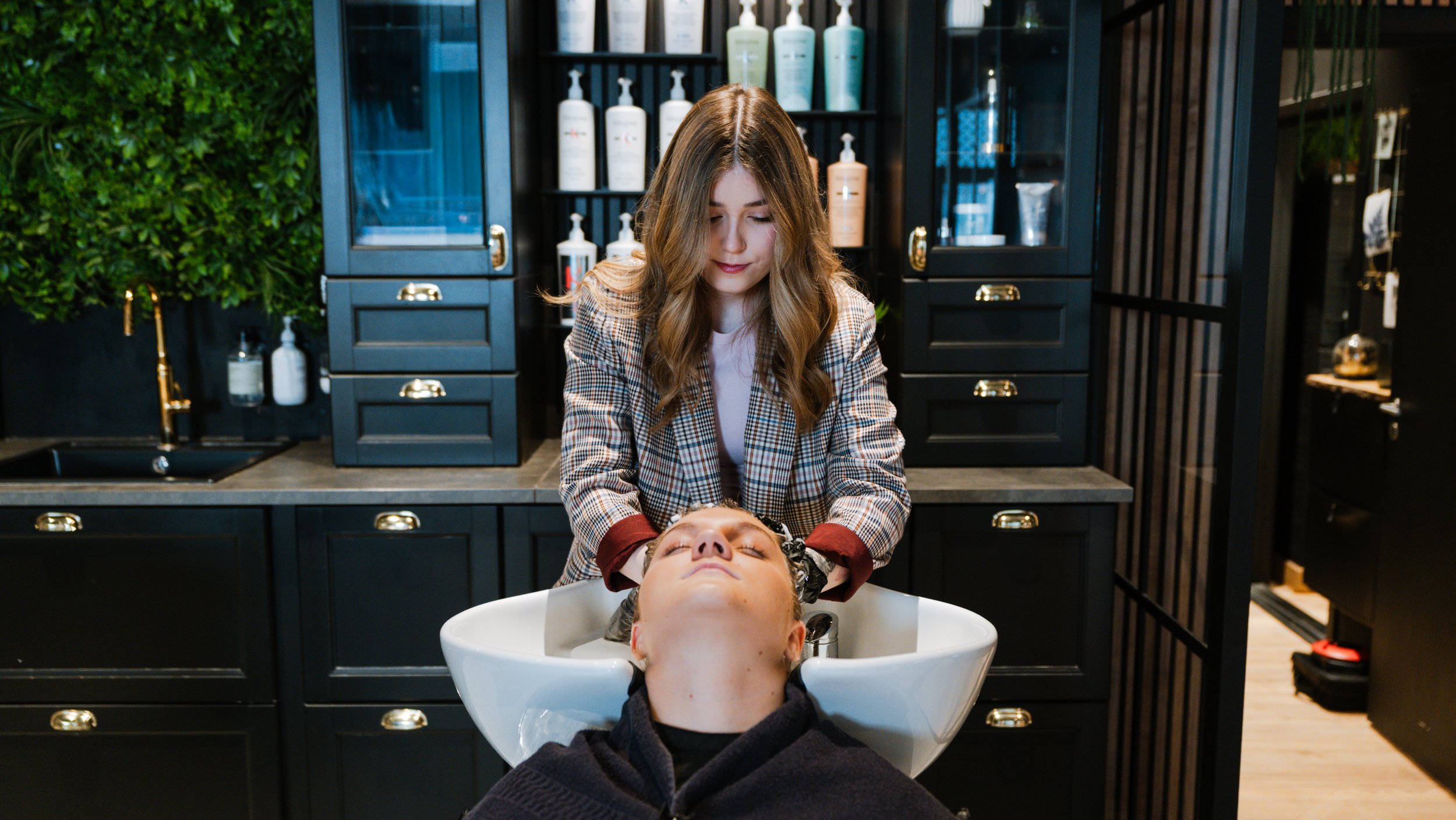 En kvinde får shampoo i håret af en frisør i en frisørsalon.