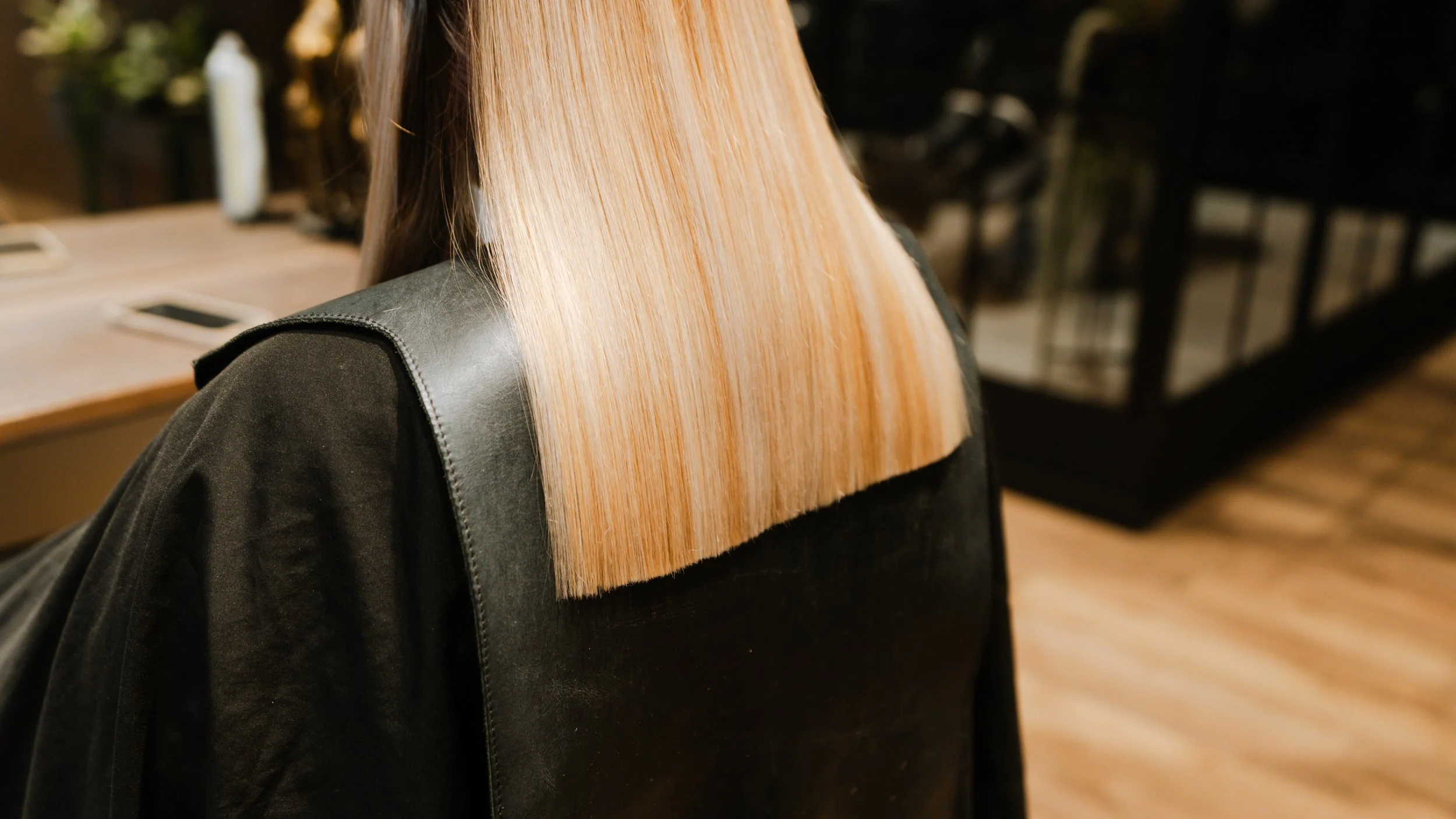 Person med langt, lyst blondt, lige hår, set bagfra, i en frisørstol.