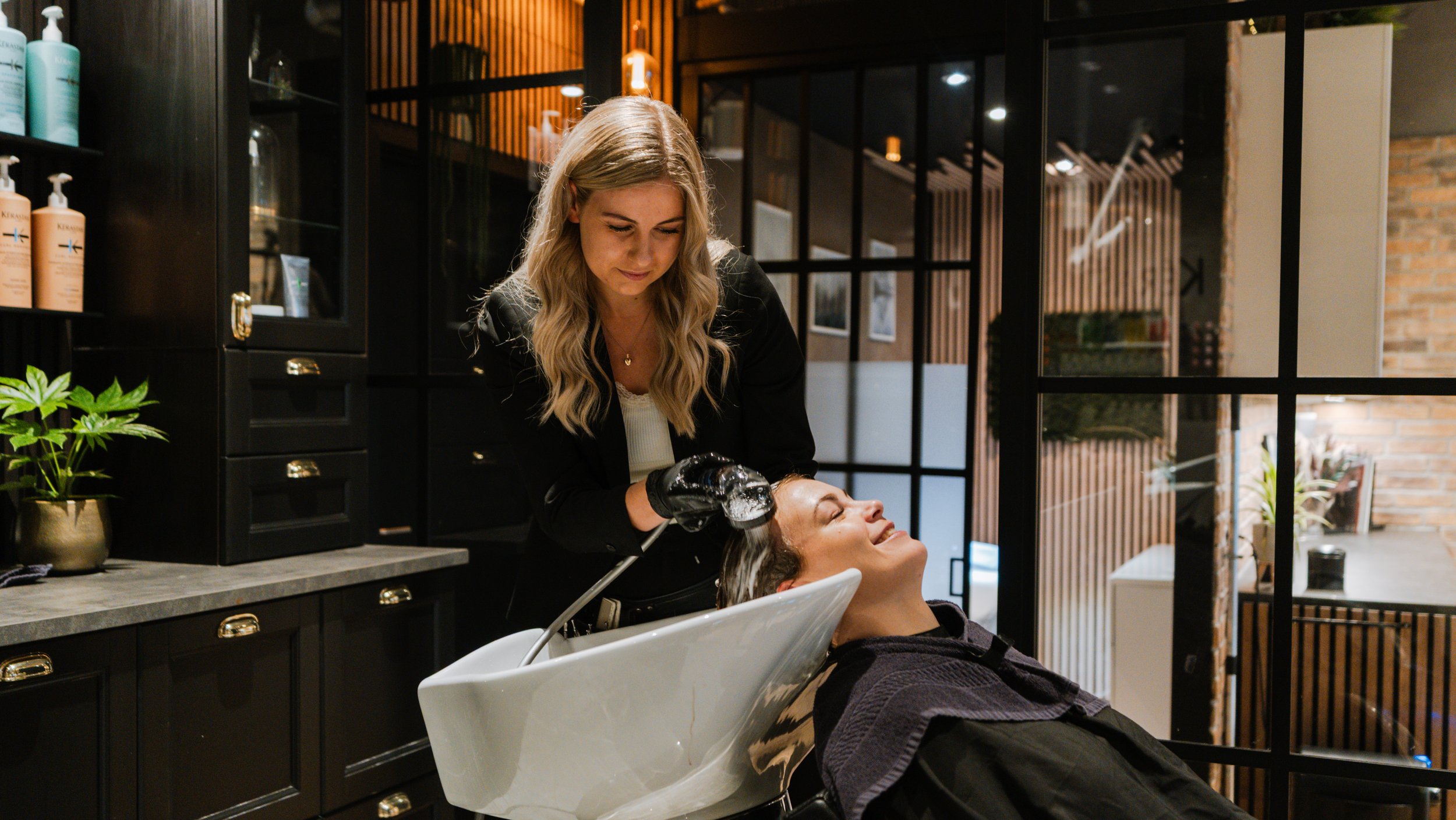 En frisør giver en kunde hovedvask i en salon med moderne indretning.