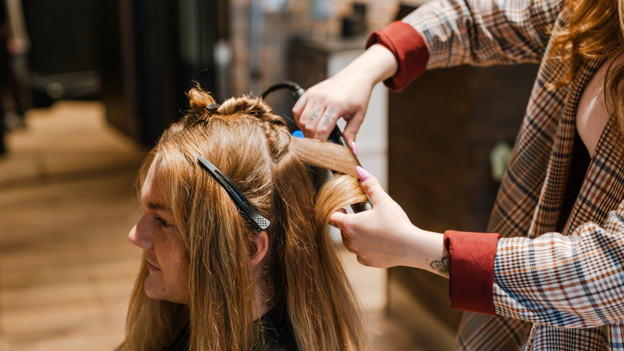 En frisør, der klipper en kvindes lysebrune hår i en frisørsalon.
