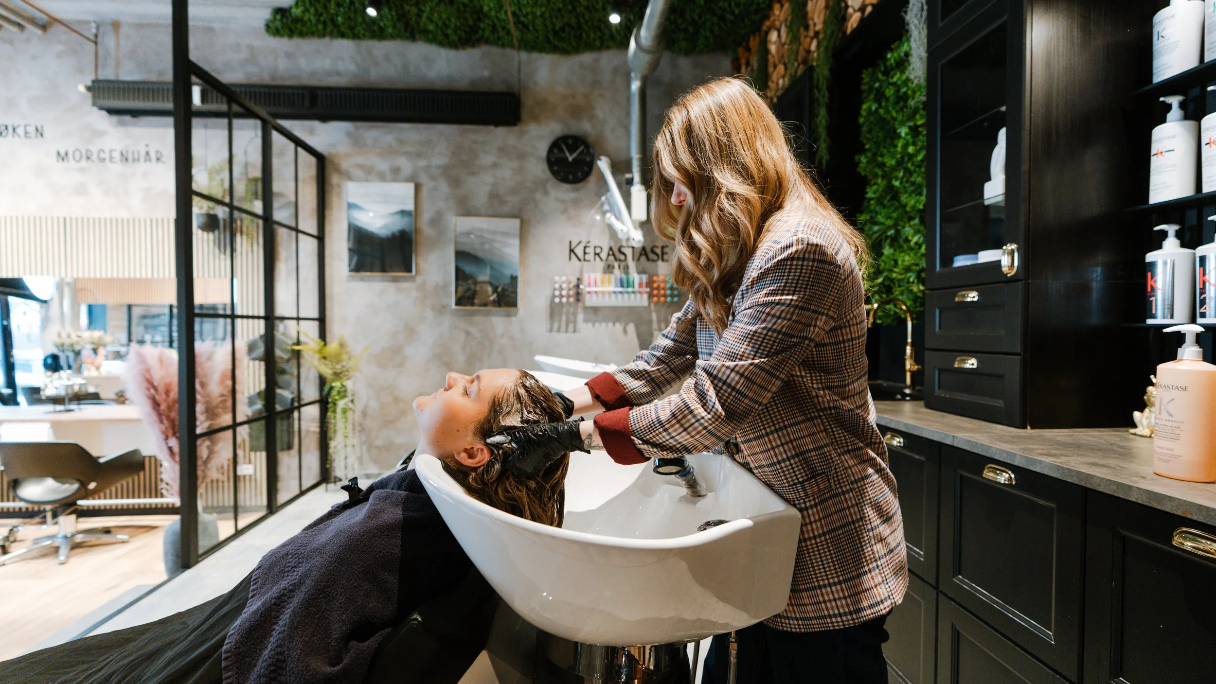 En frisør, der vasker en kundes hår i en salon.