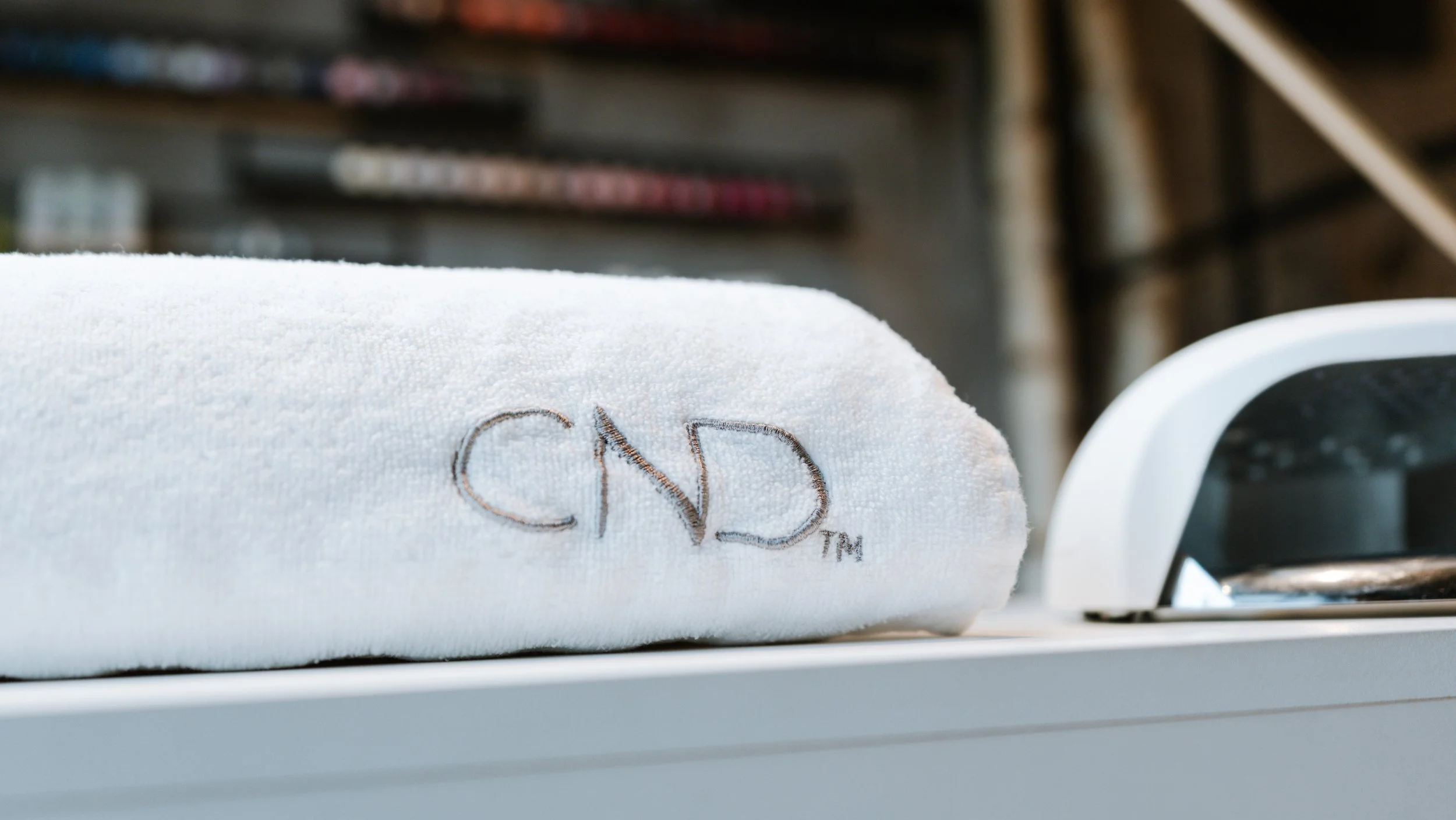 Hvid håndklæde med logoet 'CND' broderet på det